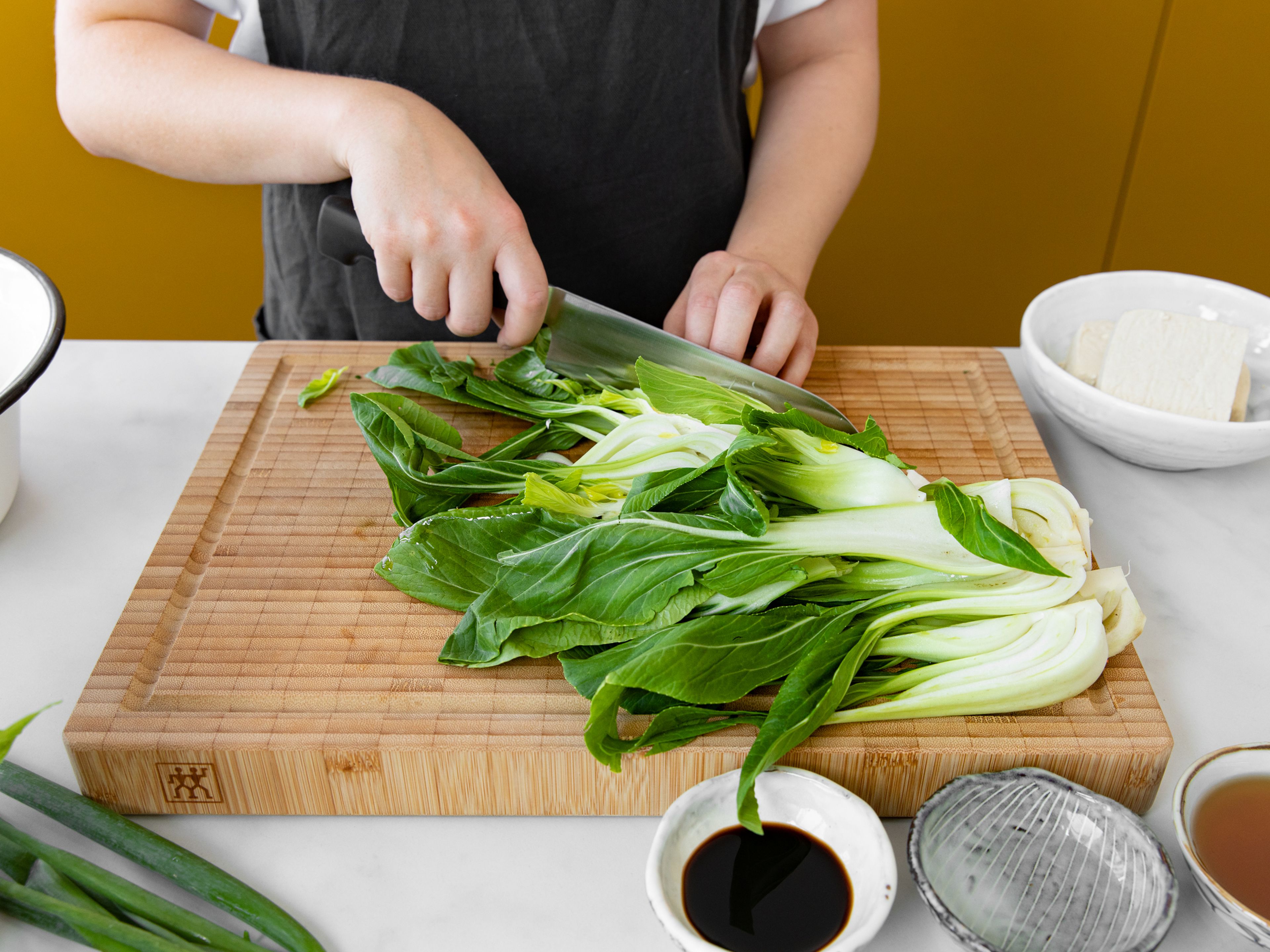 Peel and finely dice scallion and garlic. Deseed chili and slice into thin rings. Trim the ends off bok choy heads and slice each lengthwise into strips.