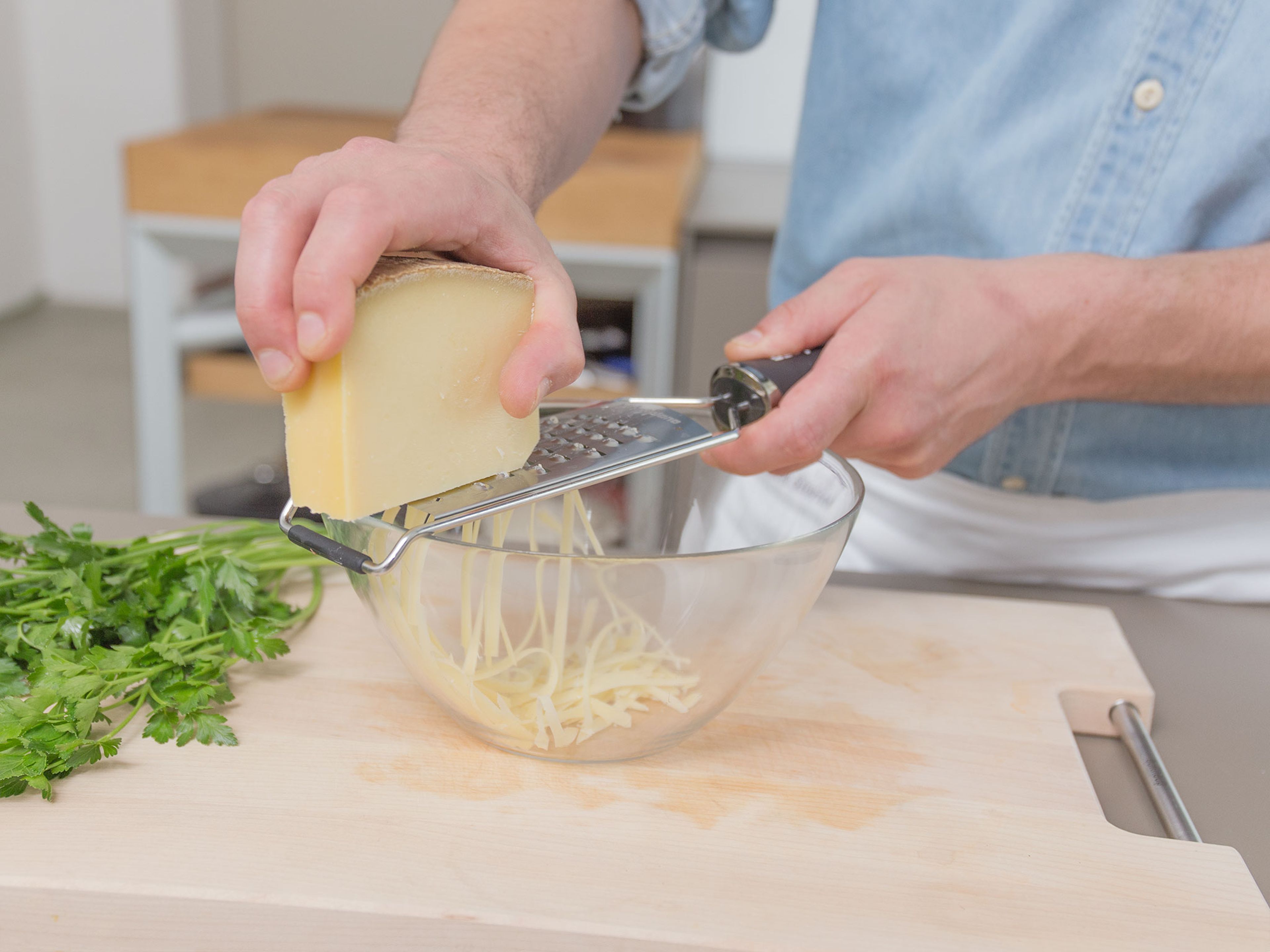 Käse reiben. Petersilie hacken und beiseitestellen. Salat waschen und in eine große Schüssel geben.