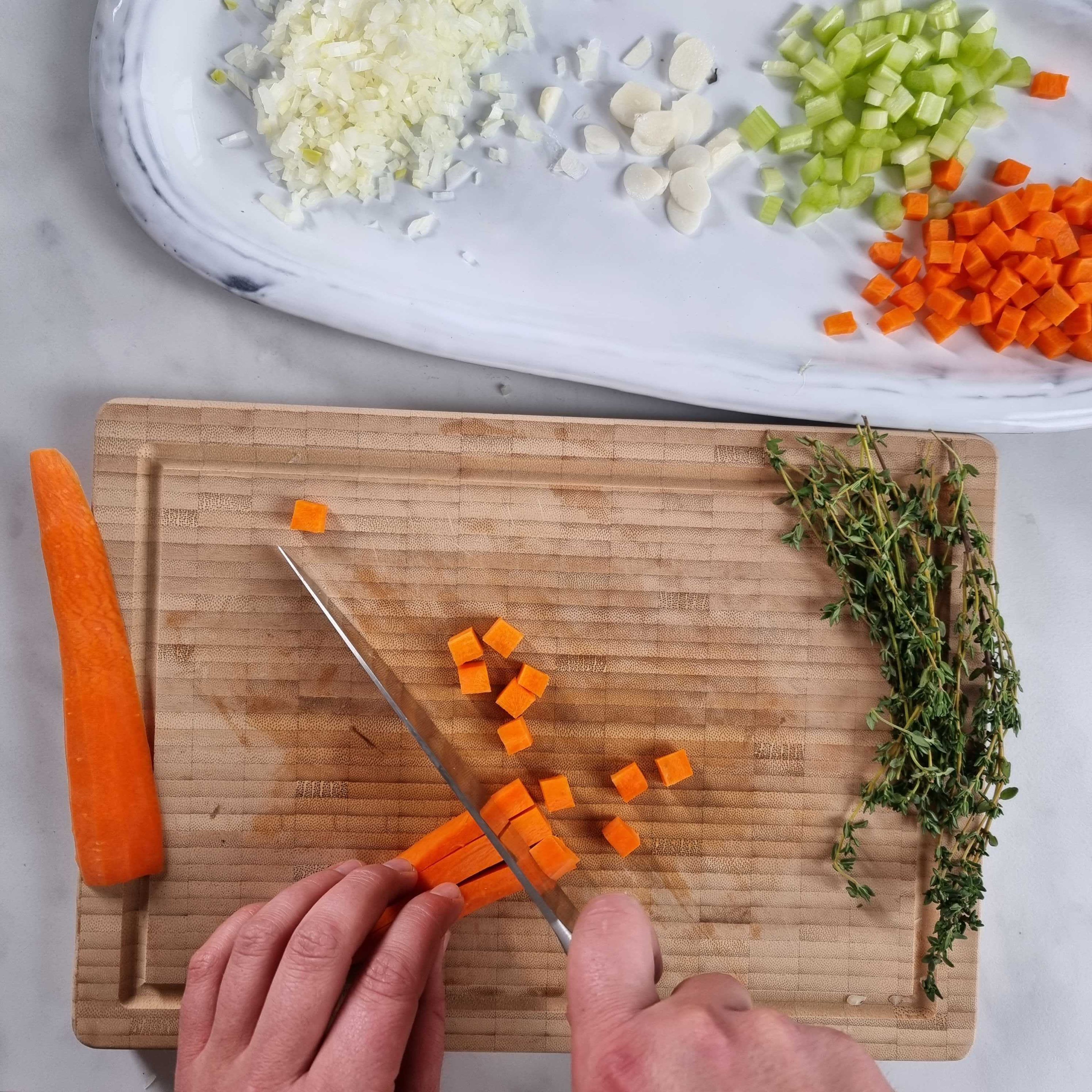 Finely chop the garlic and onions. Cut the celery and carrots into cubes. Finely chop the rosemary and thyme. Drain the canned tomatoes in a sieve, reserving the liquid. Then crush the tomatoes with your fingers.