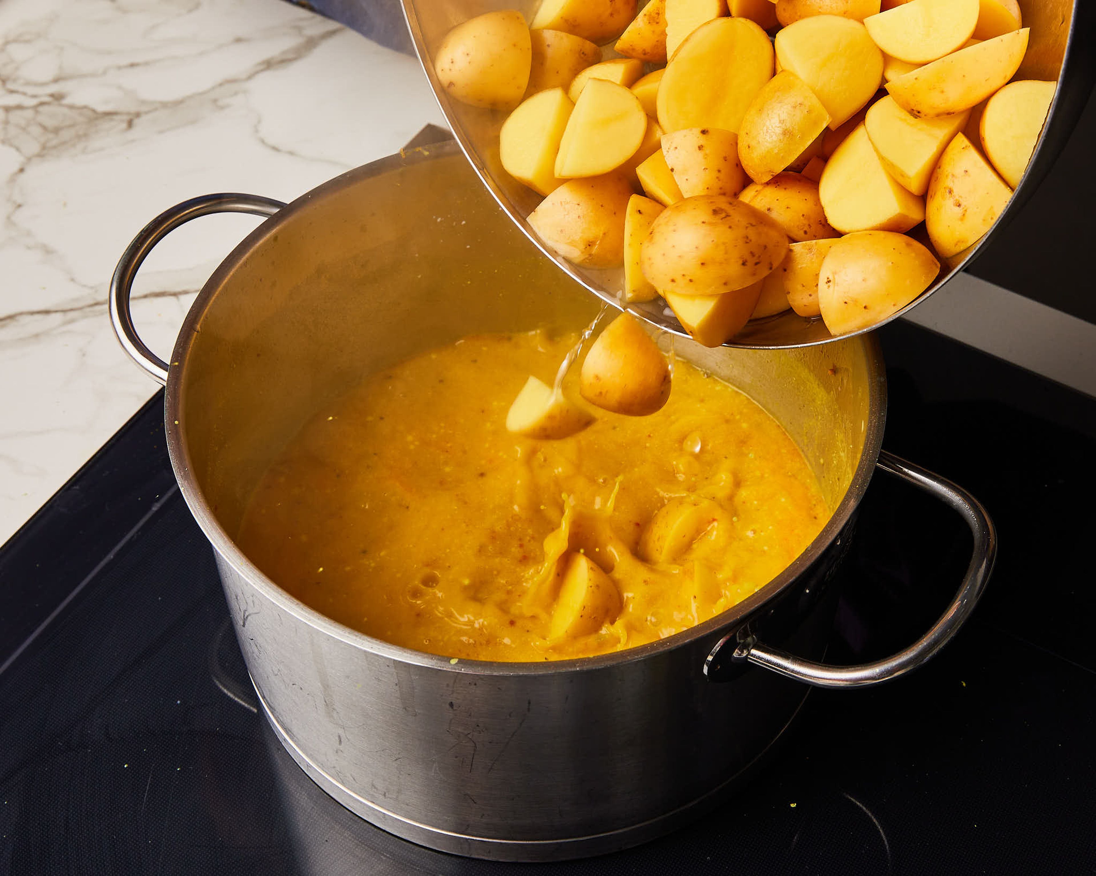 Kokosmilch, Wasser, Limettenabrieb und -saft, Salz und Pfeffer hinzufügen. Kartoffeln einrühren, abdecken und zum Kochen bringen. Dann die Hitze reduzieren und ca. 20–25 Min. köcheln lassen.