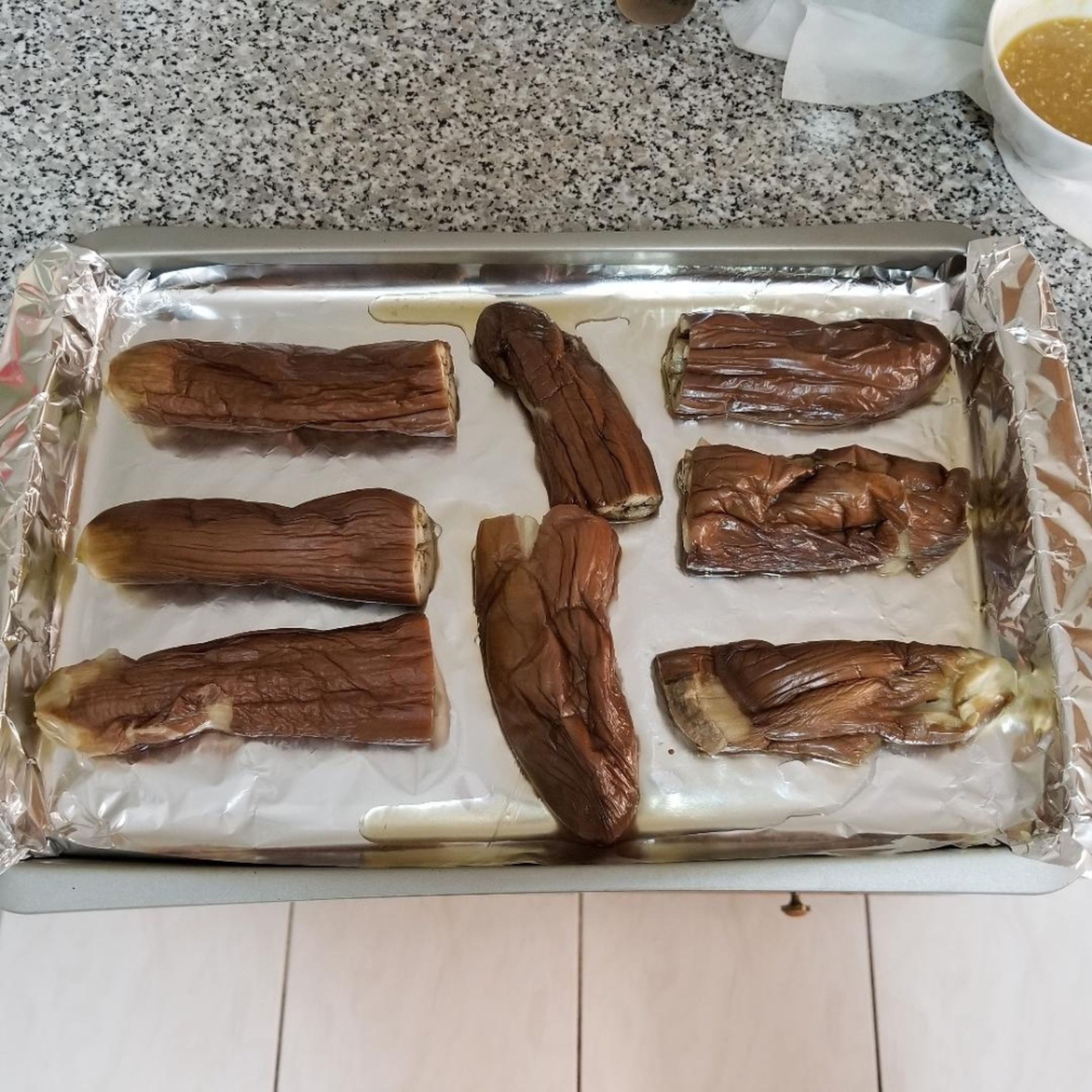 Carefully move eggplants onto an aluminum foil lined baking tray. Note the eggplants will be super soft, so use a pair of tongs to move (chopsticks won't work!)