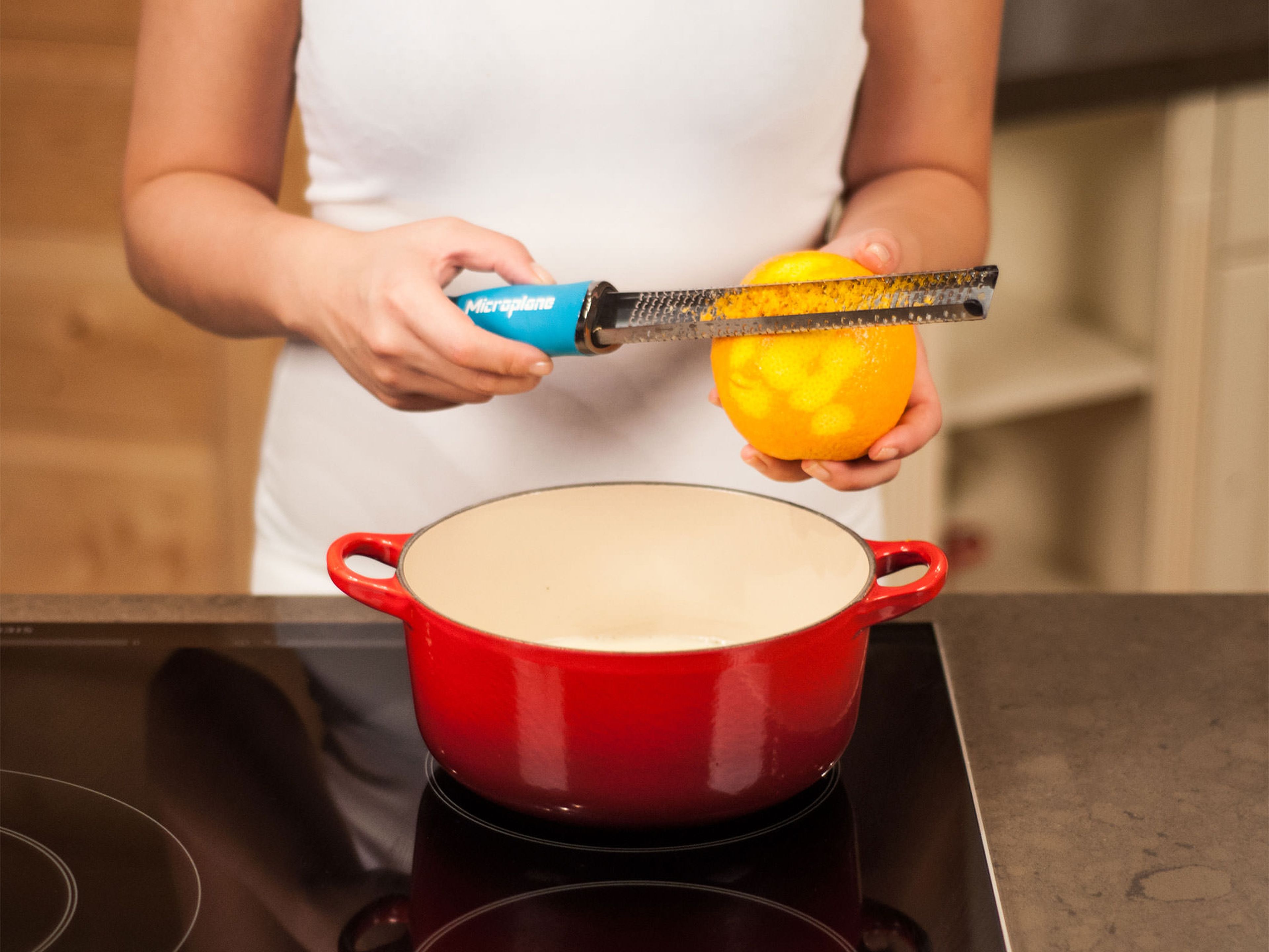 Restliche Sojamilch zusammen mit Teilen des Zuckers, dem Vanillemark sowie Zitronen- und Orangenabrieb in einen großen Topf geben. Aufkochen, dann auf ein Köcheln reduzieren. Dabei gelegentlich umrühren.