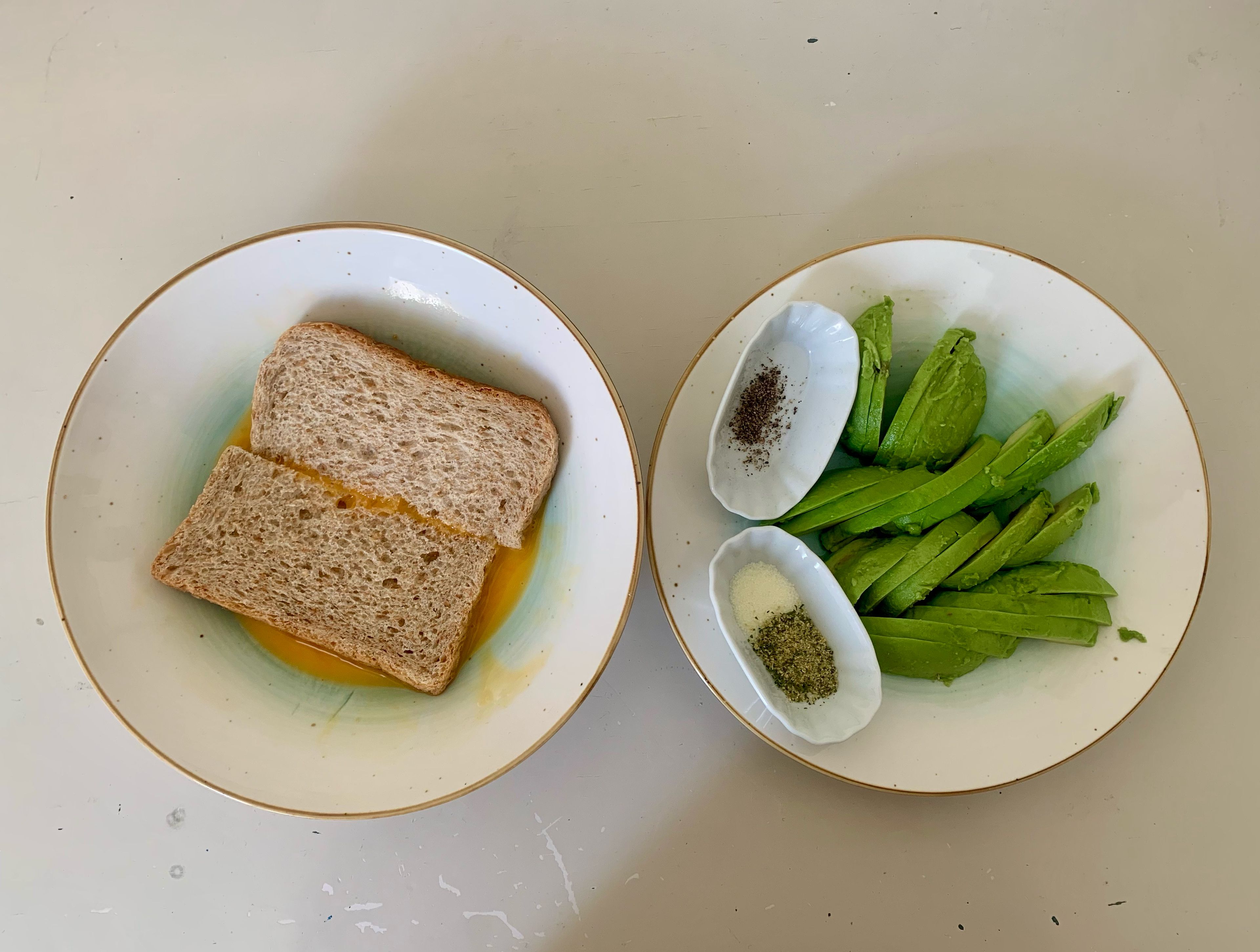 Während das Reinigungs-Programm des Cookits läuft, Avocado schneiden und Eier verquirlen und das Toastbrot halbieren. Danach die Scheiben in die Eimasse geben, sodass sich die Toast-Scheiben vollsaugen.