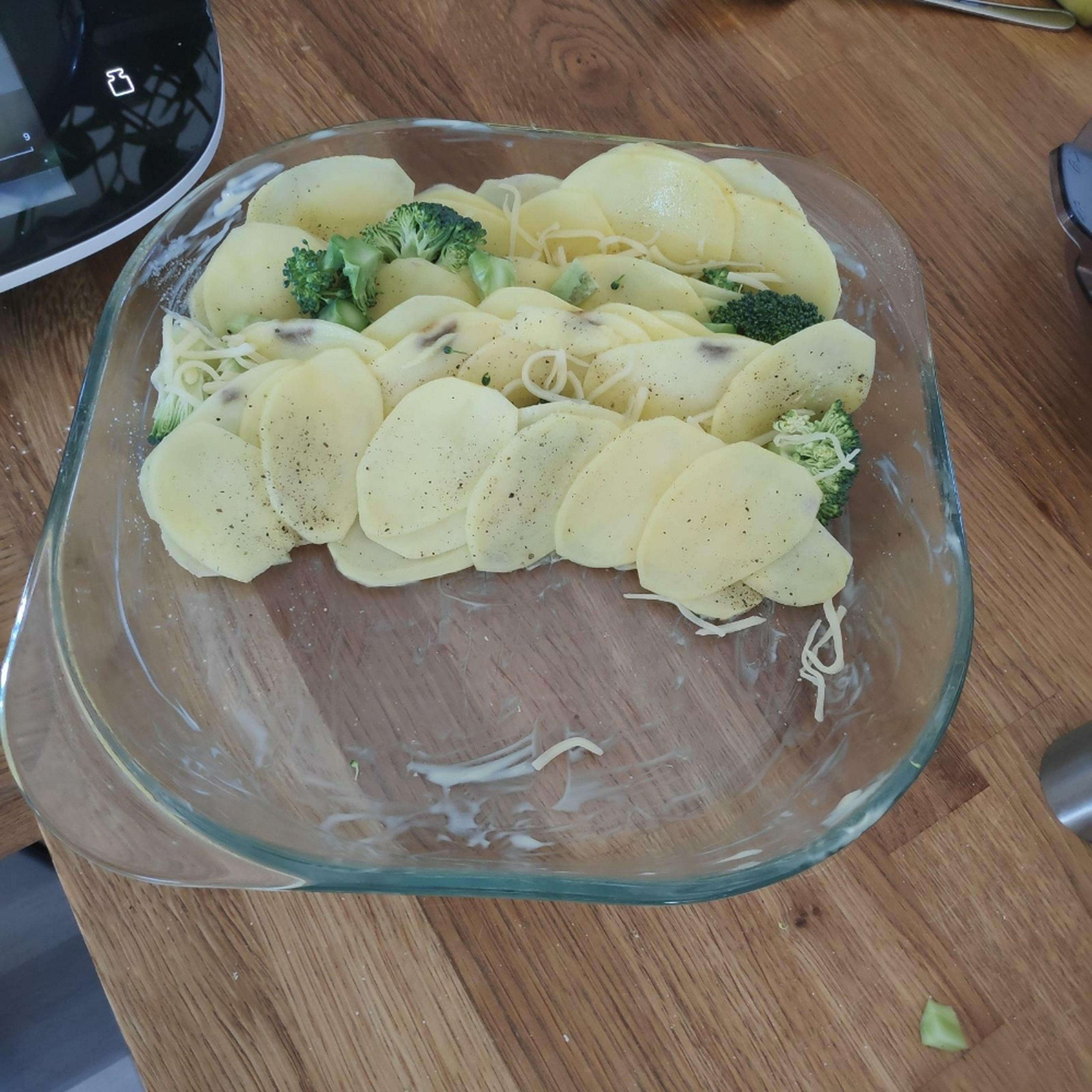 Nun die Kartoffelscheiben, den Brokkoli und etwas von dem Käse im Wechsel in eine vor gefettete Form schichten. Hierbei die Schichten immer wieder zwischendurch würzen.