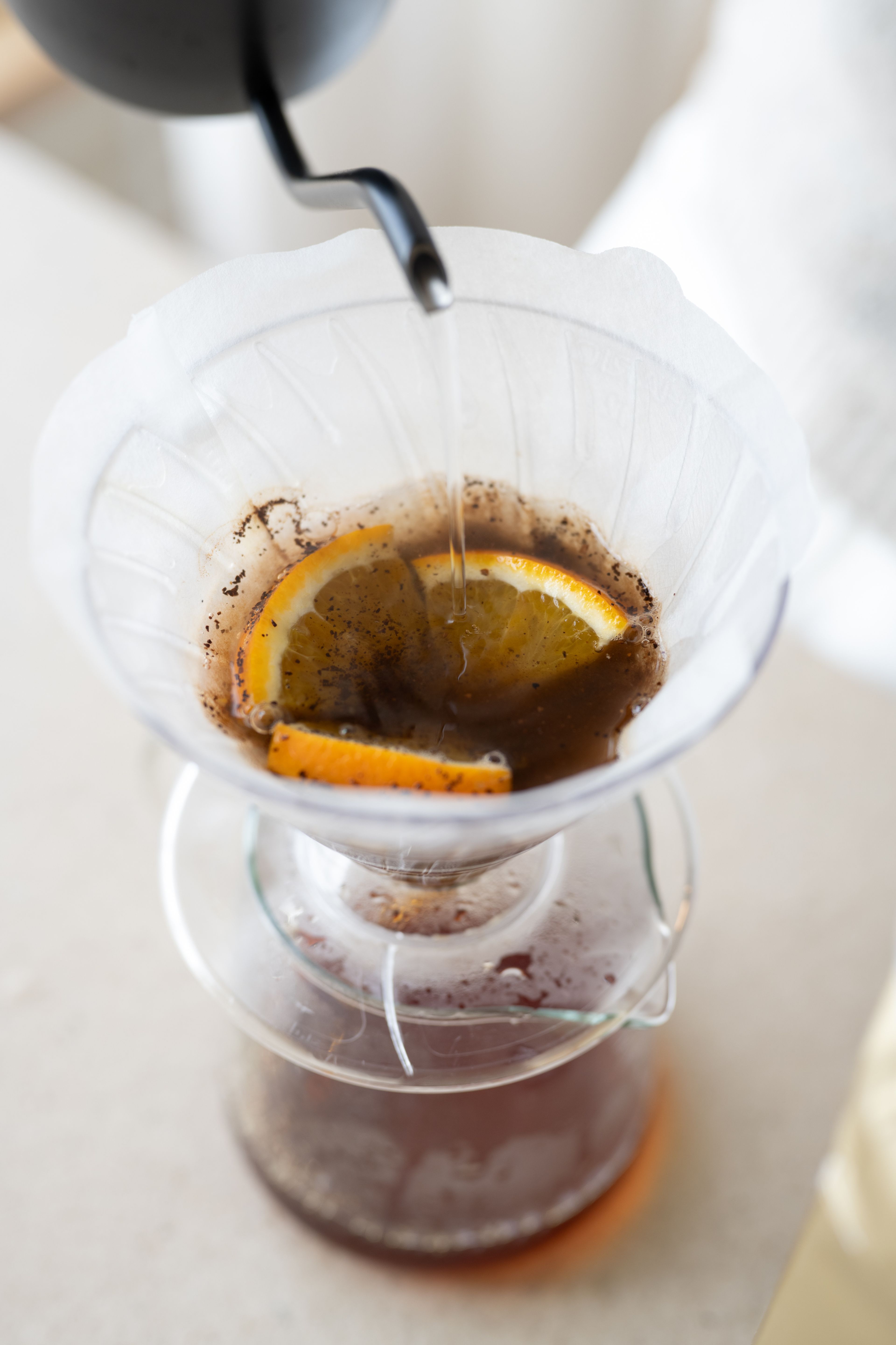 Kaffee in den Filter geben. Eine Scheibe Orange dritteln und auf dem Kaffee platzieren.