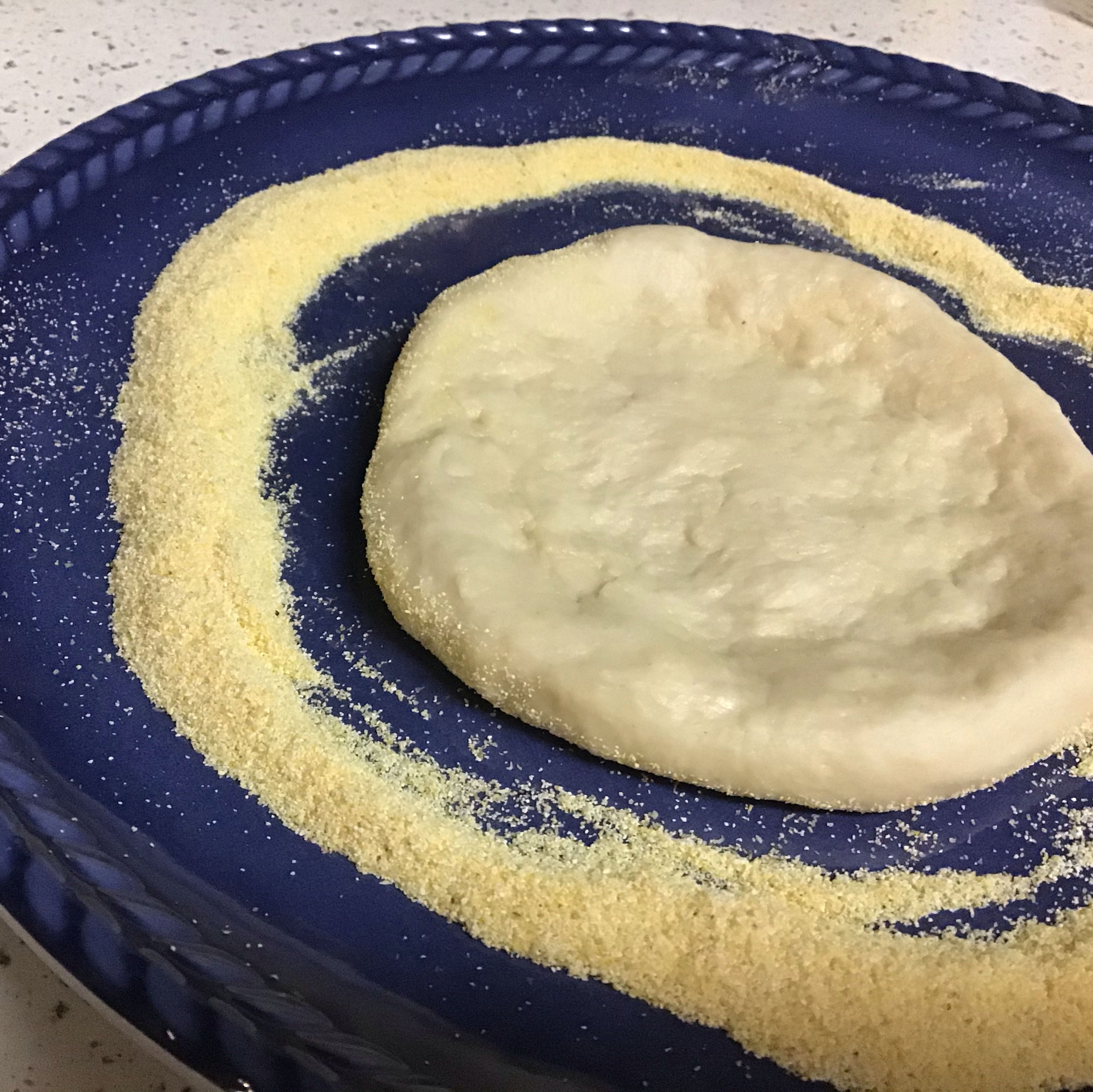 Open the dough in a clean surface dusted with the cornmeal with the finger tips in a round shape, leaving an small edge, place in a greased and floured pan. Make some holes in the dough using a fork