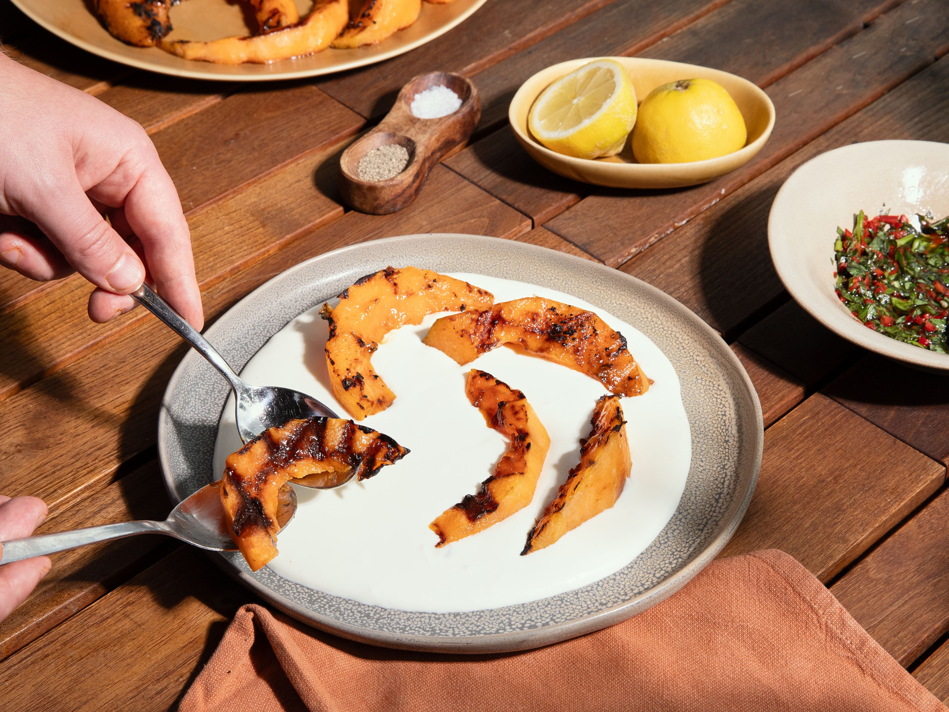 Die Fetacreme auf einem Teller verstreichen. Die gegrillte Melone darauf geben, mit dem Chili-Basilikum-Öl beträufeln und mit Basilikumblättern und Zitronenzeste garnieren. Dazu passt geröstetes Brot vom Grill.