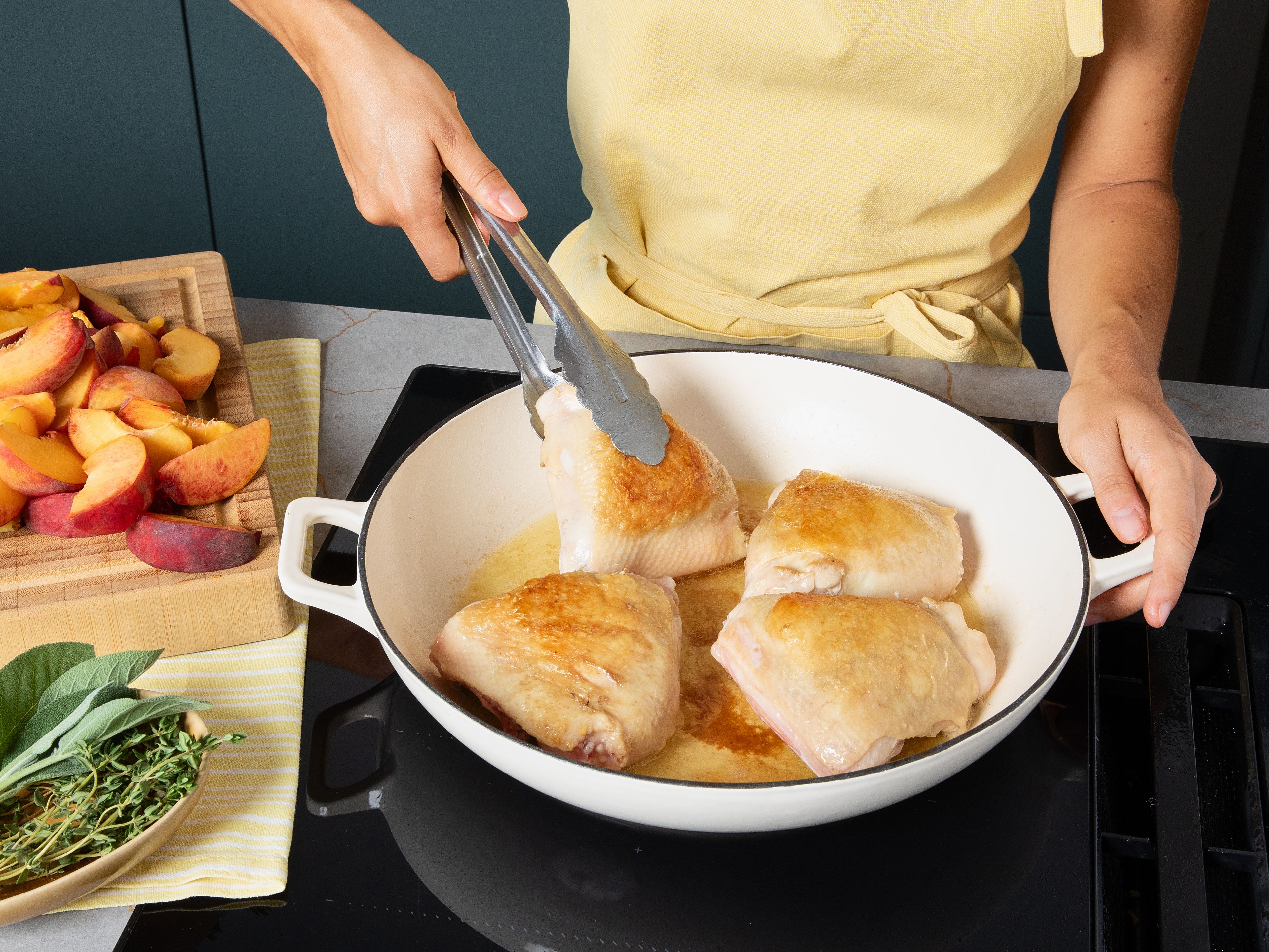 Preheat oven to 200°C/392°F. Finely chop garlic, cut shallots and peaches into wedges. Rub chicken thighs thoroughly with salt. Heat olive oil in ovenproof pan and sear chicken thighs on both sides for approx. 5 min., until golden brown. Remove chicken from pan.