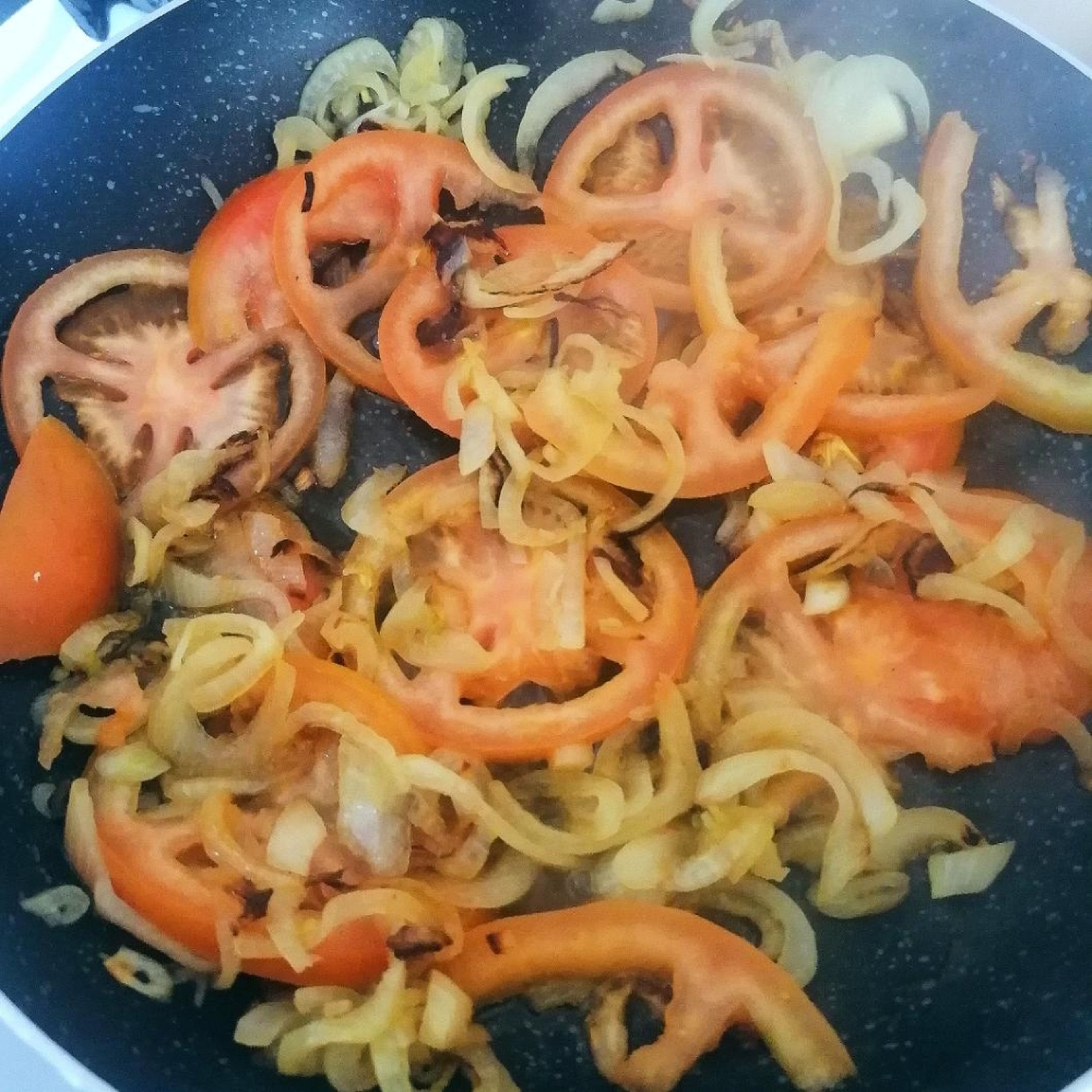 Heat the olive oil in a pan. Add the sliced onion and let it fry for 3 min. Add the tomato slices and keep them frying until they become soft.