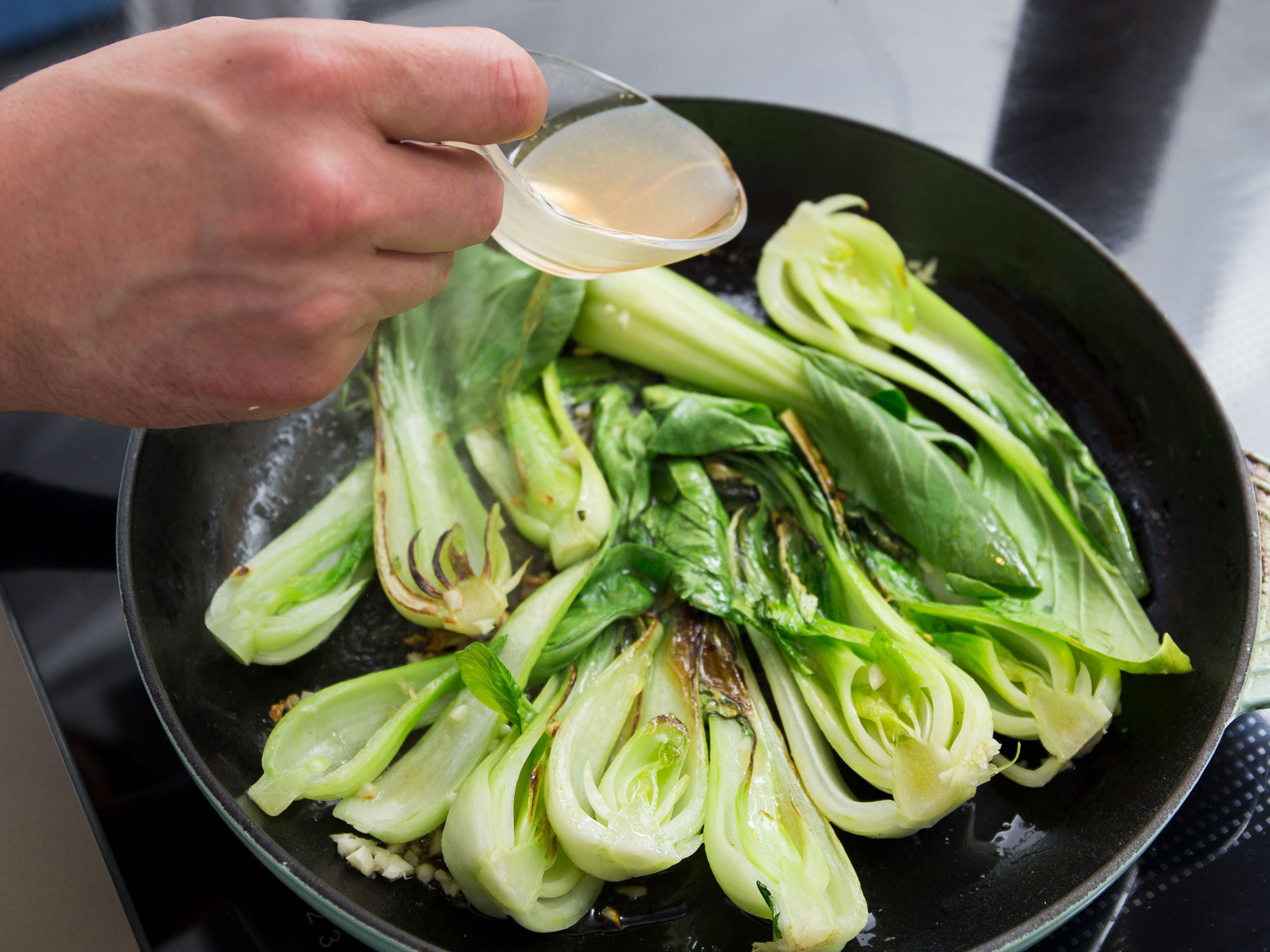 Heat oil in a large frying pan set over medium-low heat. Fry half of the chopped garlic for approx. 1 – 2 min., then add baby bok choy. Season with salt and pepper. Deglaze with vegetable stock and cover pan with lid. Cook for approx. 3 – 4 min. or until bok choy is soft but firm to the bite.