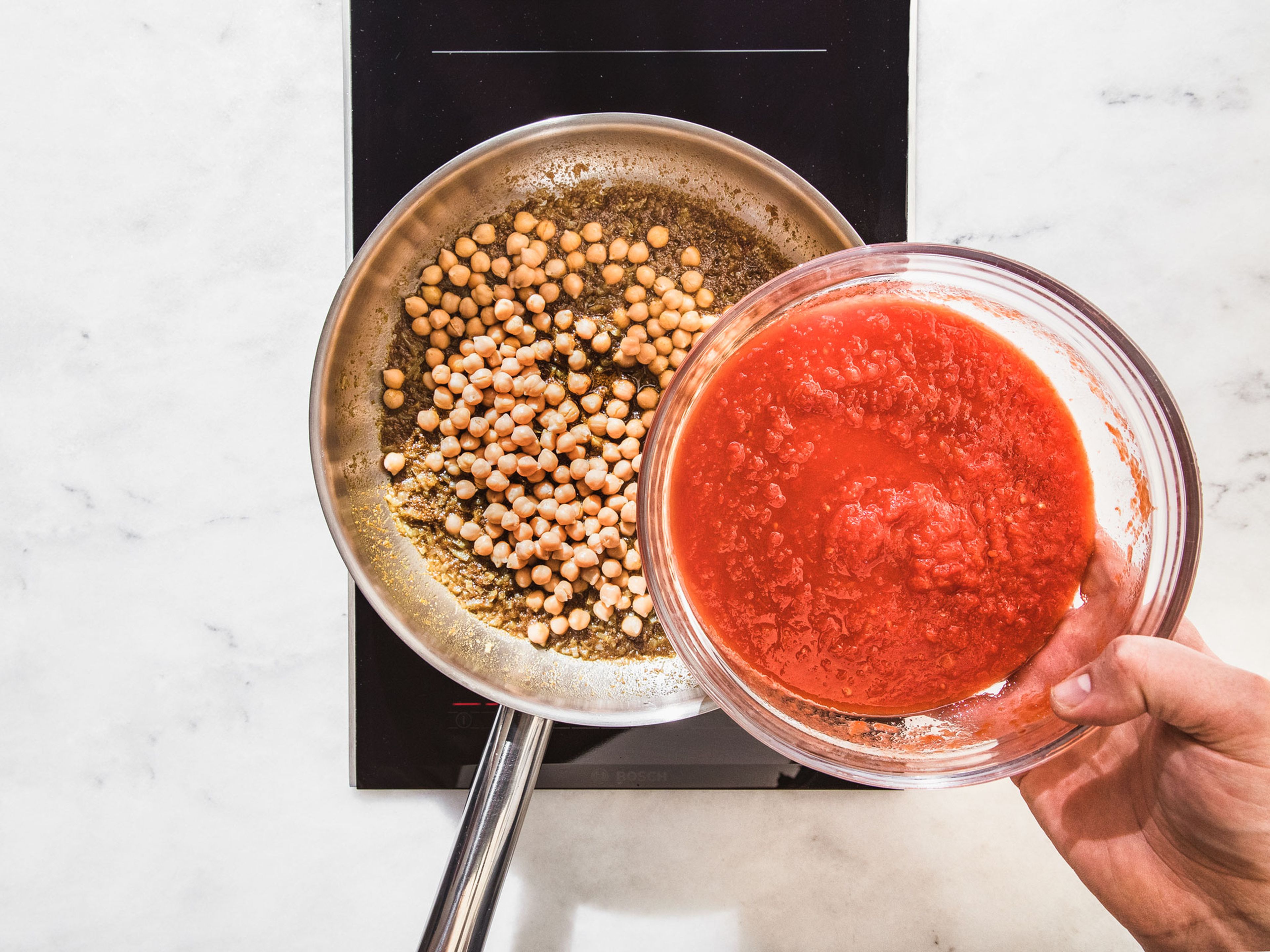 Heat ghee in a frying pan over medium heat. Add onion and sauté for approx. 5 min., or until translucent. Add spice paste, drained chickpeas, crushed tomatoes, and water and let simmer for approx. 10 min.