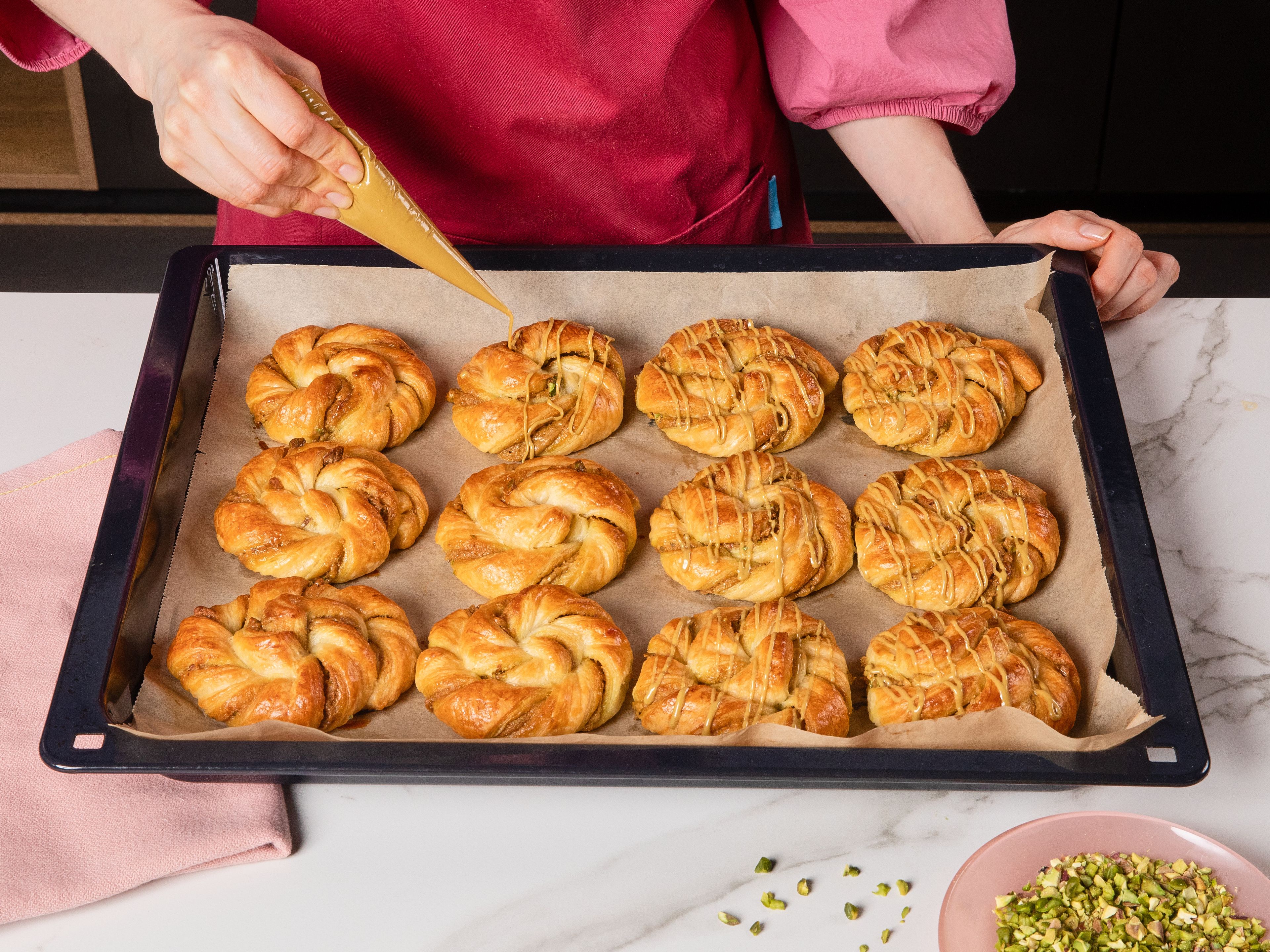 Die Nester in den vorgeheizten Backofen geben und ca. 15–18 Min. goldbraun backen und anschließend kurz abkühlen lassen. Dann die restliche Pistaziencreme in feinen Linien über die Nester geben und mit den restlichen gehackten Pistazien bestreuen.