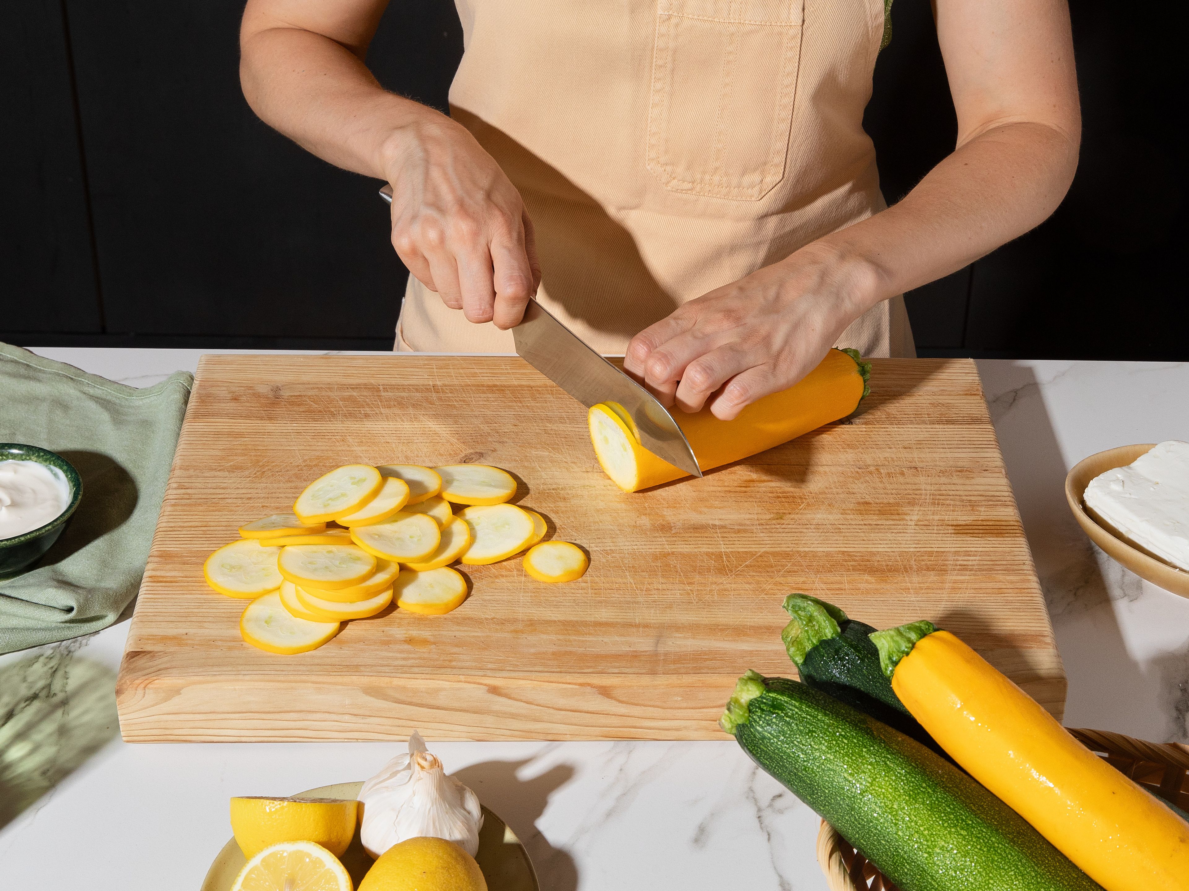 Preheat oven to 200°C/ 400°F. Slice zucchini very thinly using a mandoline or knife. Sprinkle with a little salt and let sit for approx. 10–15 min. to draw out excess moisture. Pat dry with paper towels. Meanwhile, crumble the feta and mix with crème fraîche, finely grated garlic, lemon zest, and some pink pepper and salt. For an extra creamy consistency, you can briefly purée the mixture with an immersion blender.