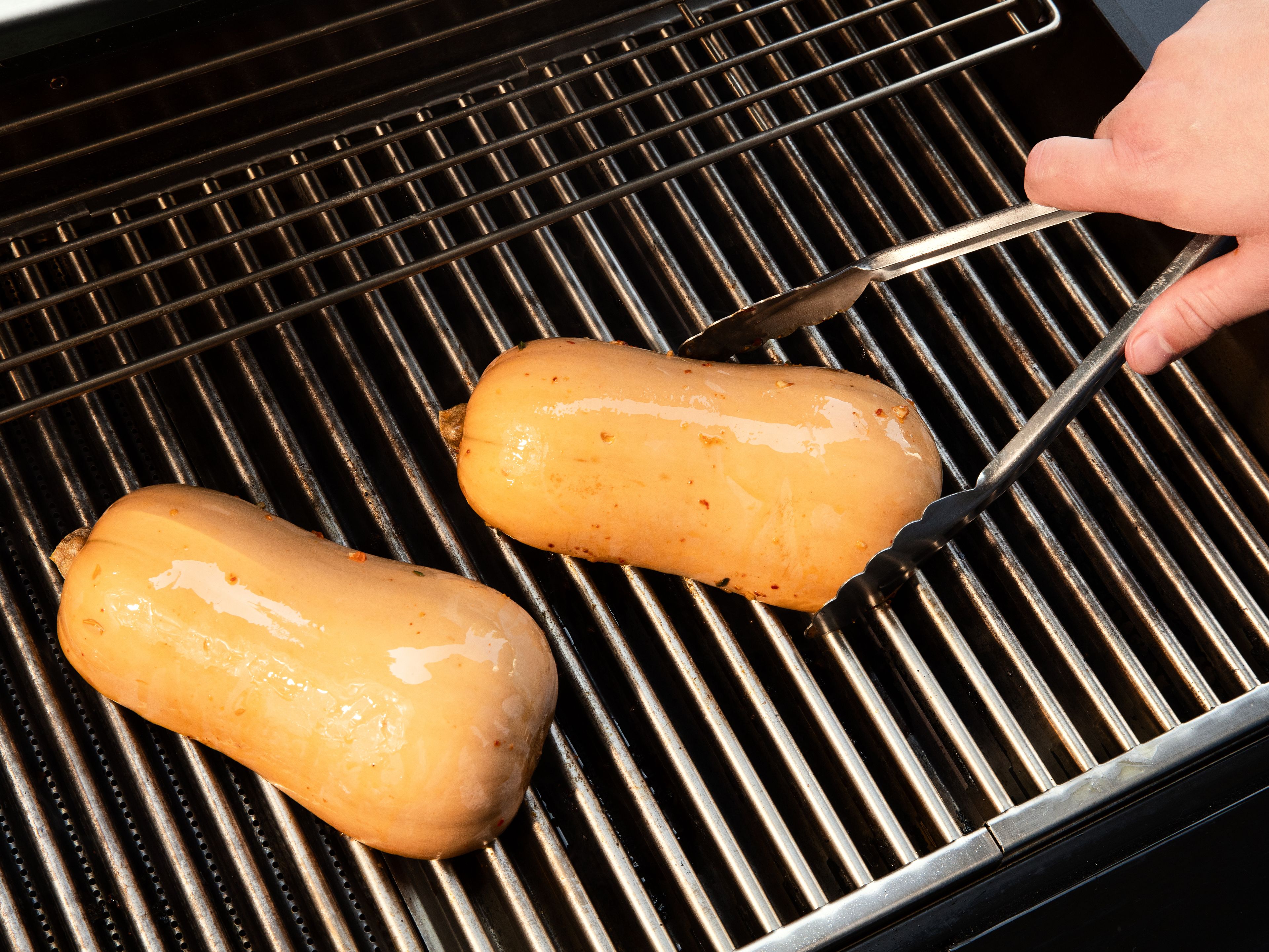 Die Schnittflächen der Kürbishälften mit der Marinade einpinseln und ca. 20 Min. ziehen lassen. Anschließend mit der Schnittfläche nach unten auf den Grillrost legen und bei geschlossenem Deckel ca. 35–40 Min. grillen, bis das Fruchtfleisch weich ist.
