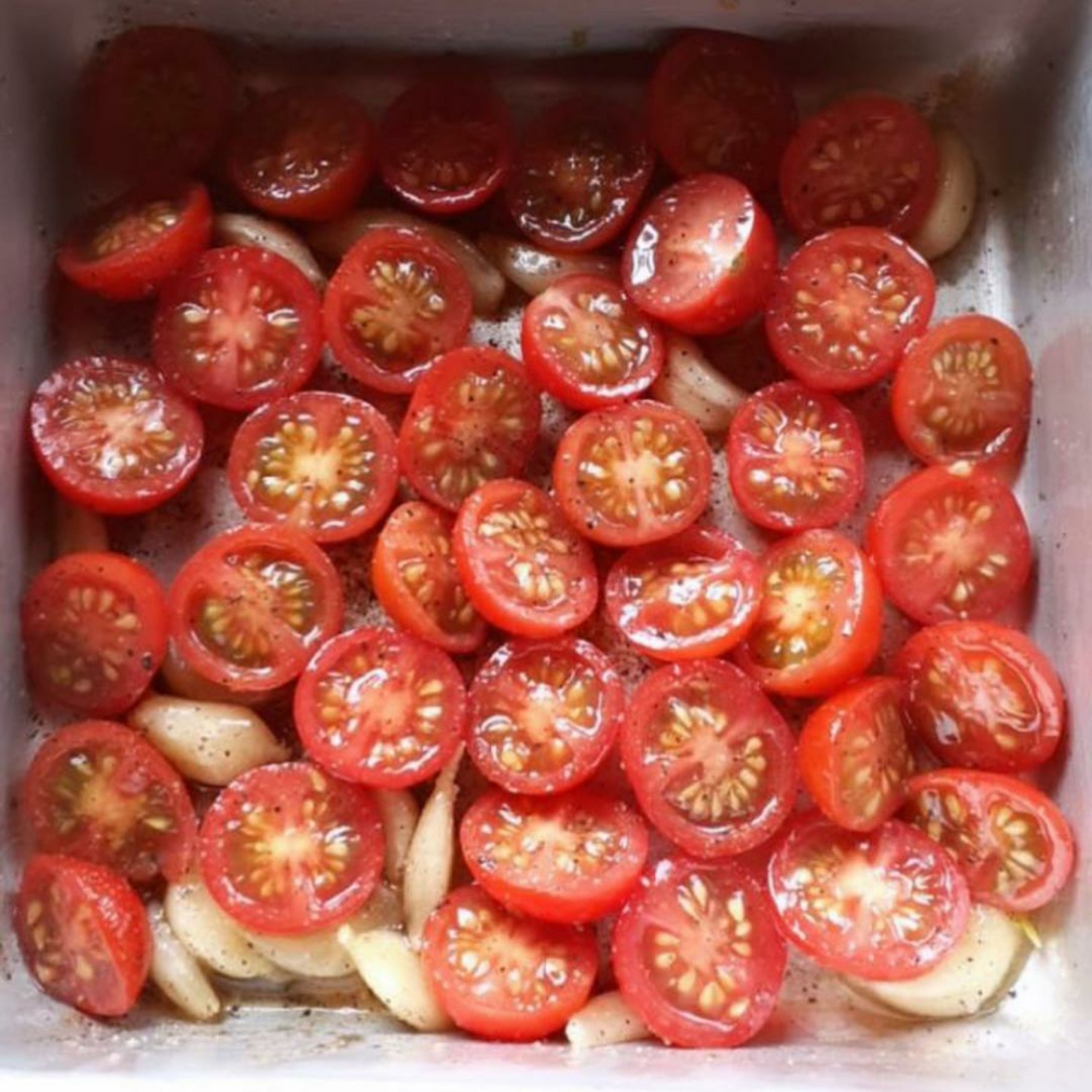 Halve the cherry tomatoes and place in a baking tray along with 5 cloves of garlic, sprinkle salt, black pepper powder and 2 tsp olive oil and toss well. Note: The the cut side of the tomato should be facing upwards as shown in the picture. Roast in an oven at 180°C for 20 mins. Remove from the oven and set aside.