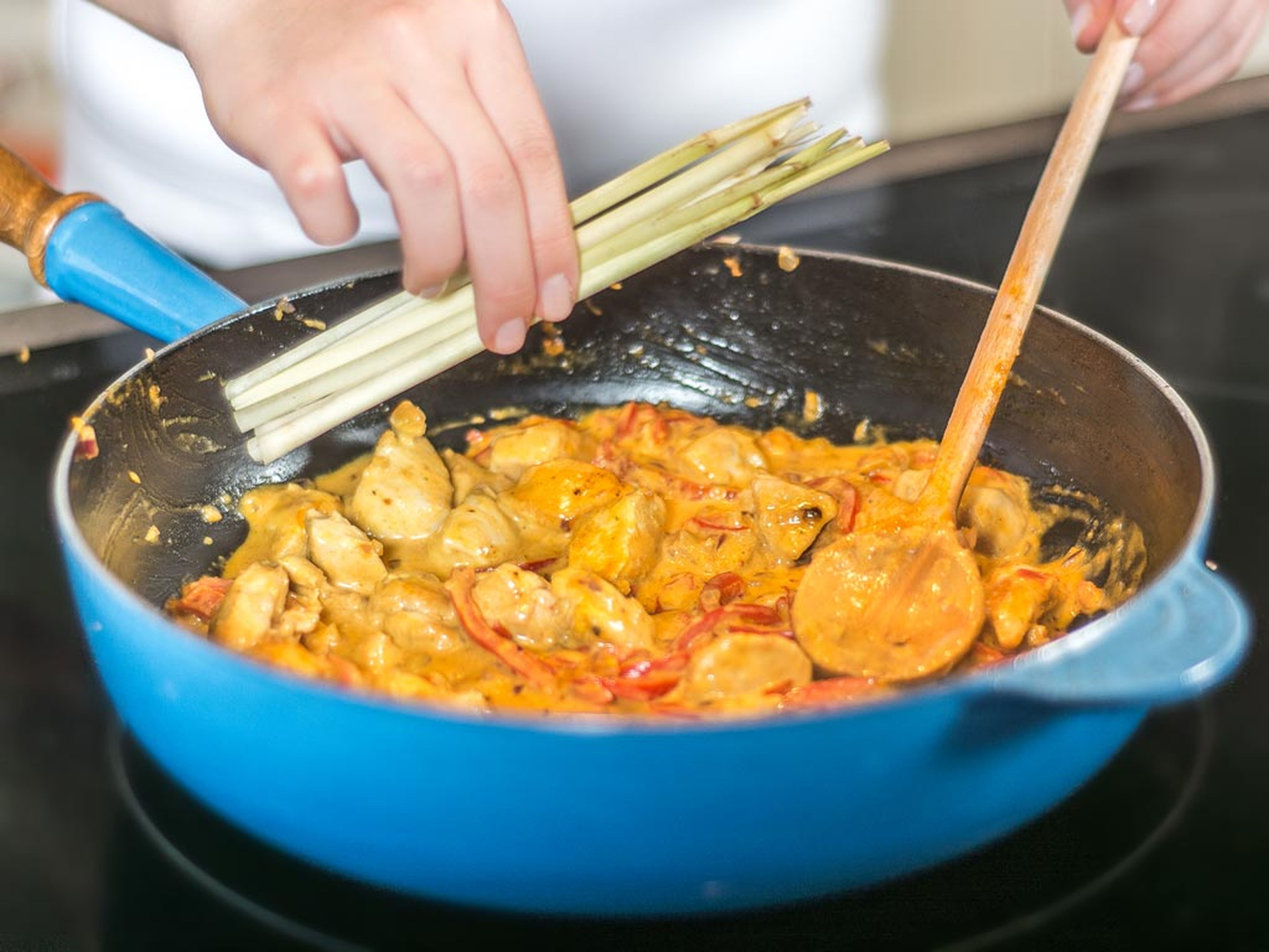 Currypaste, Kurkuma und Kokosmilch hinzugeben. Kichererbsen abtropfen lassen und mit angeklopftem Zitronengras ebenso in die Pfanne geben. Alles leicht aufkochen lassen.