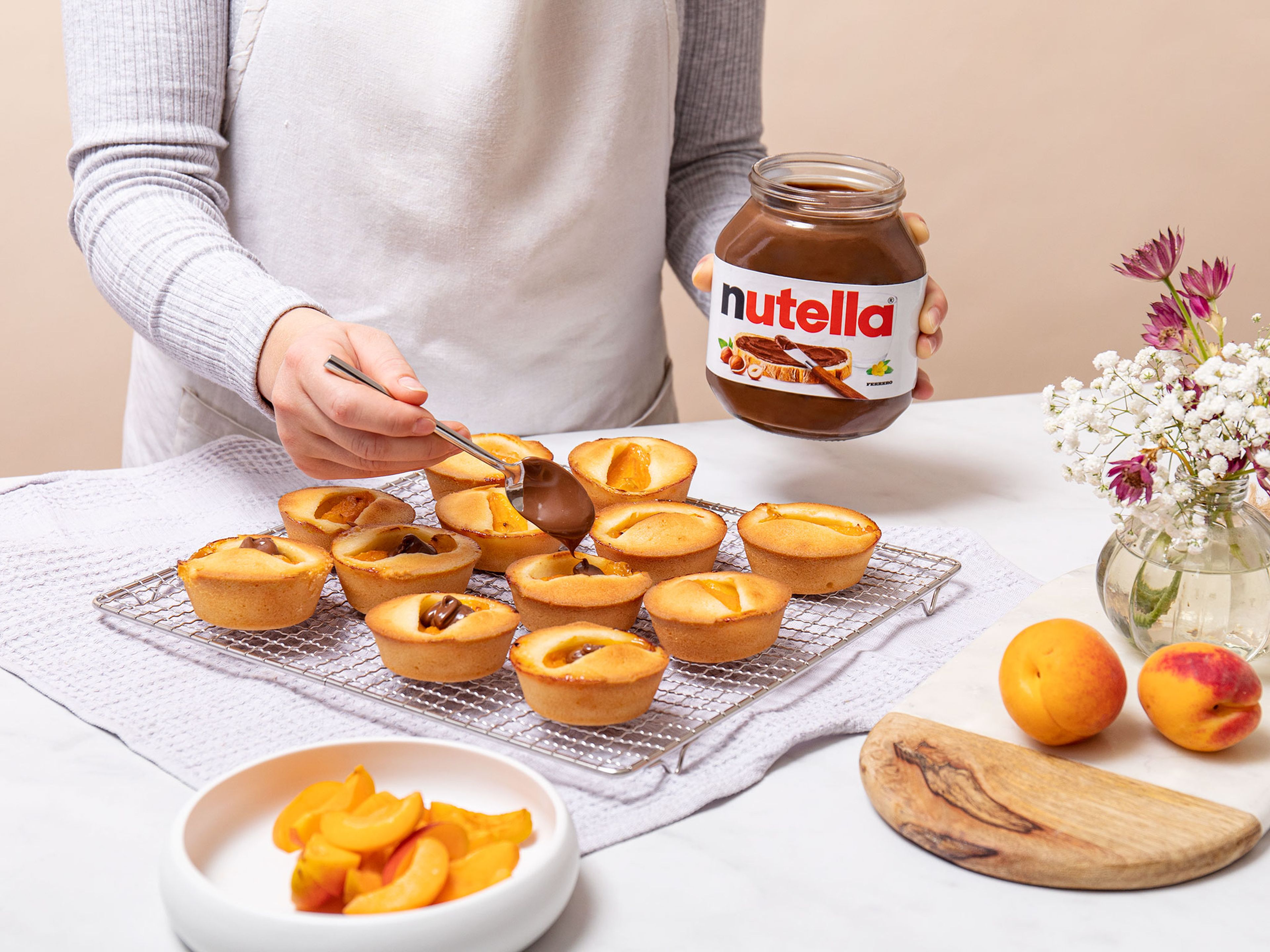 Die Muffins jeweils mit einem Klecks nutella® dekorieren und eine Aprikosenspalte auf die Creme setzen. Guten Appetit!