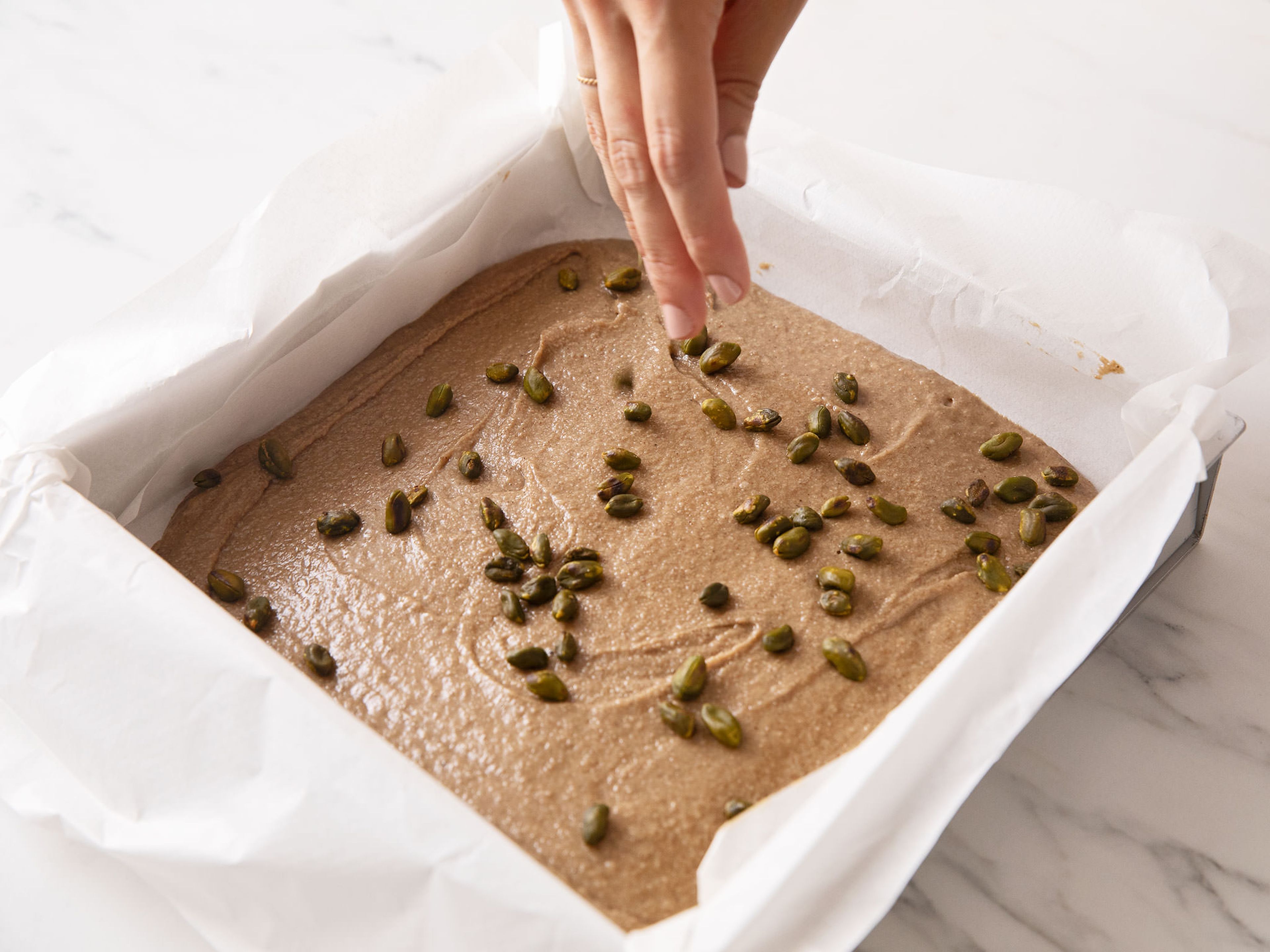 Transfer mixture immediately into a parchment paper-lined baking pan. Cover with toasted pistachios and let cool completely, approx 2 hrs. Cut into squares. Enjoy!