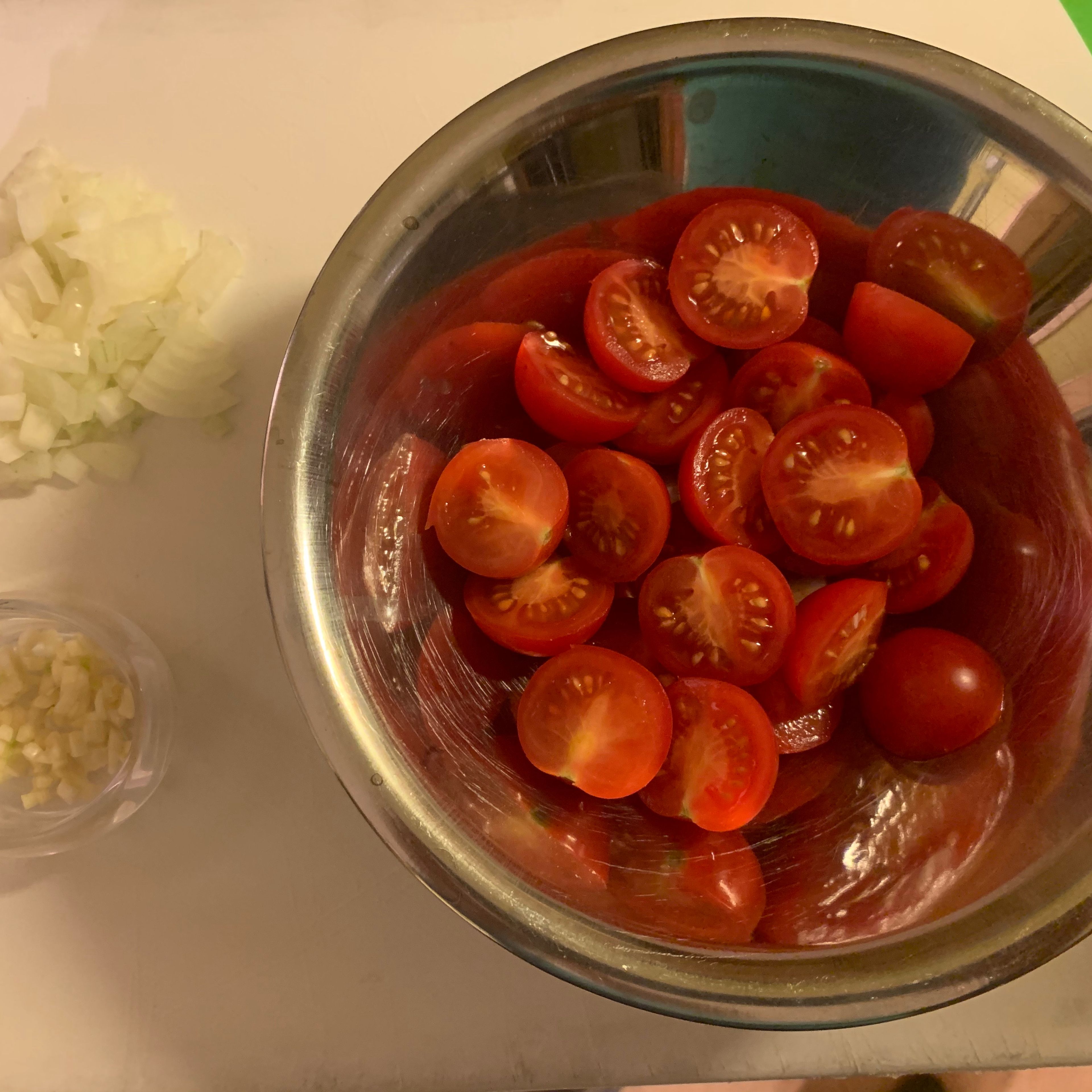 Nun die Zwiebeln und den Knoblauch in kleine Würfel schneiden. Die Tomaten halbieren