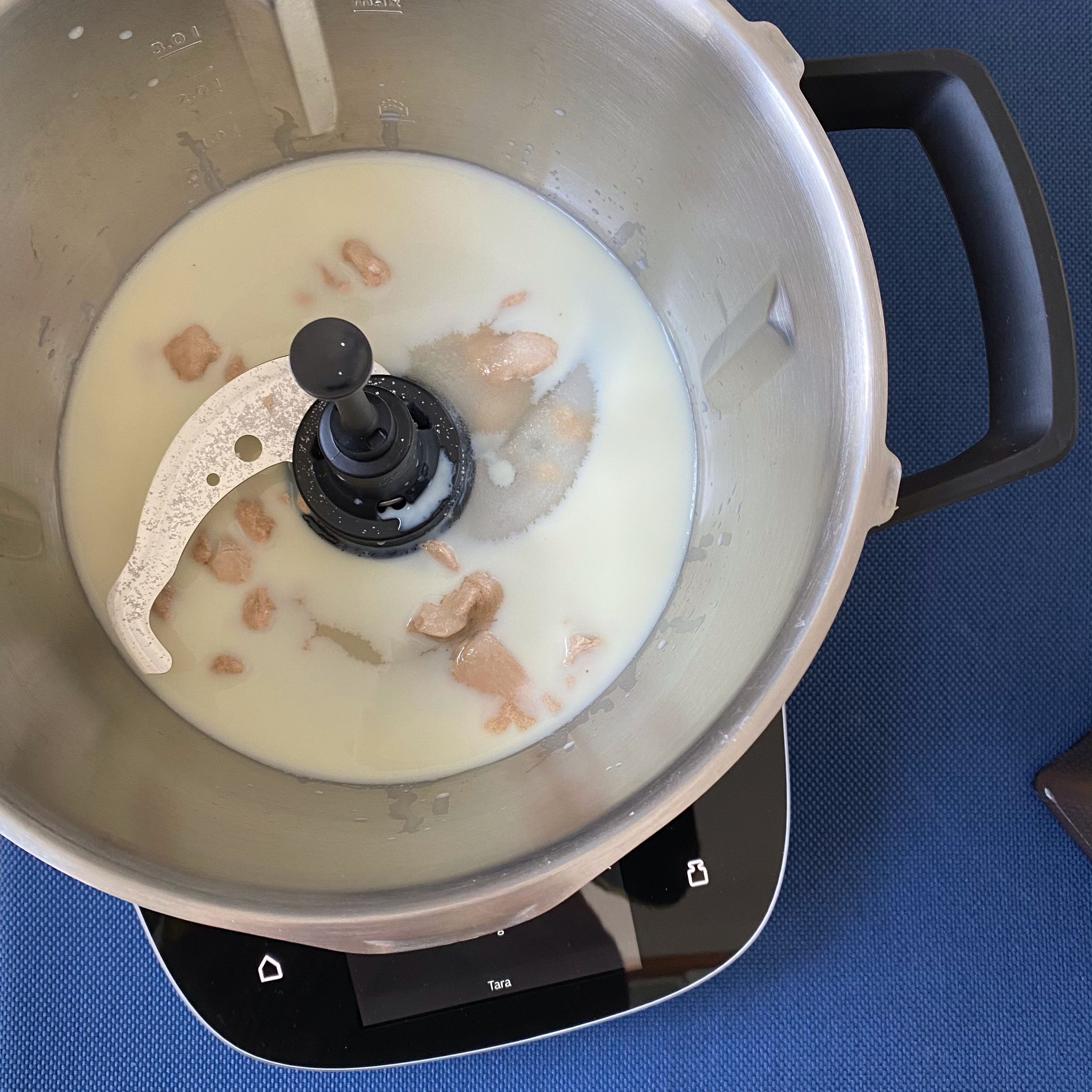 Cookit Universalmesser einsetzen. Hefe, Milch und Zucker in den Cookit einwiegen und vermischen (Universalmesser | Stufe 5 | 37°C | 3 Min.).