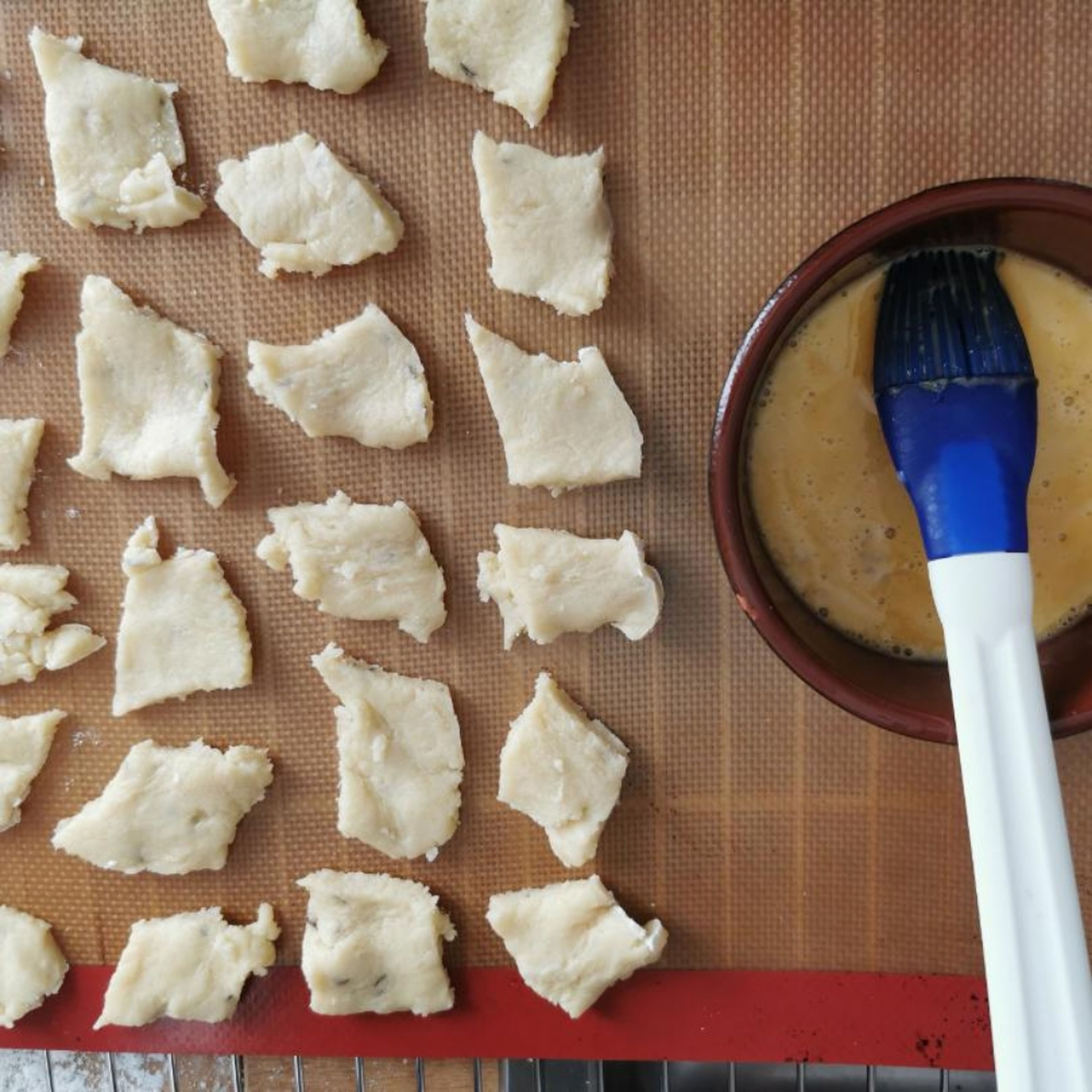 Die Kekse auf eine Backmatte aufs Backblech legen. Mit dem Silikonpinsel mit Eigelb bestreichen, dann mit ganzem Kümmel bestreuen.
