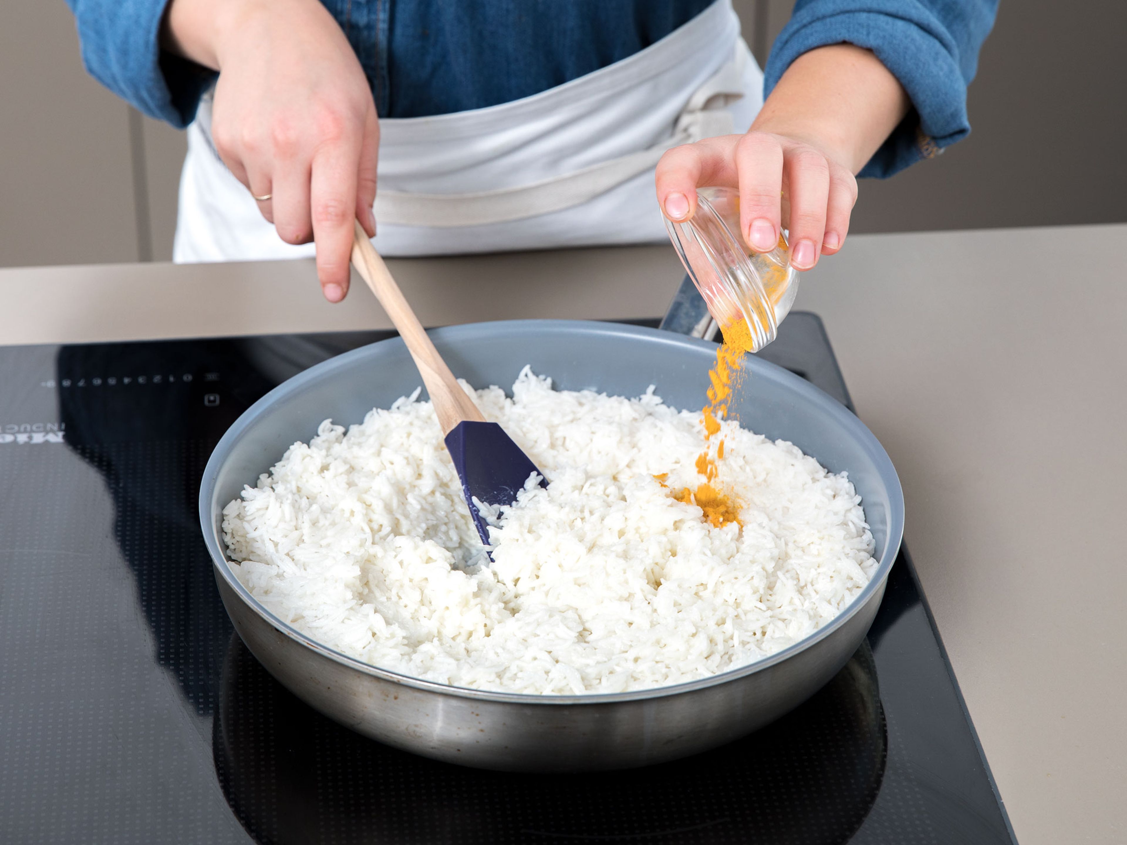 Den vorgekochten Reis, Schlagsahne, Parmesankäse und Kurkuma in eine separate Pfanne geben und durchmengen. Der Reis färbt sich leicht gelb. Ca. 5 Min. köcheln lasse und dabei hin und wieder umrühren.