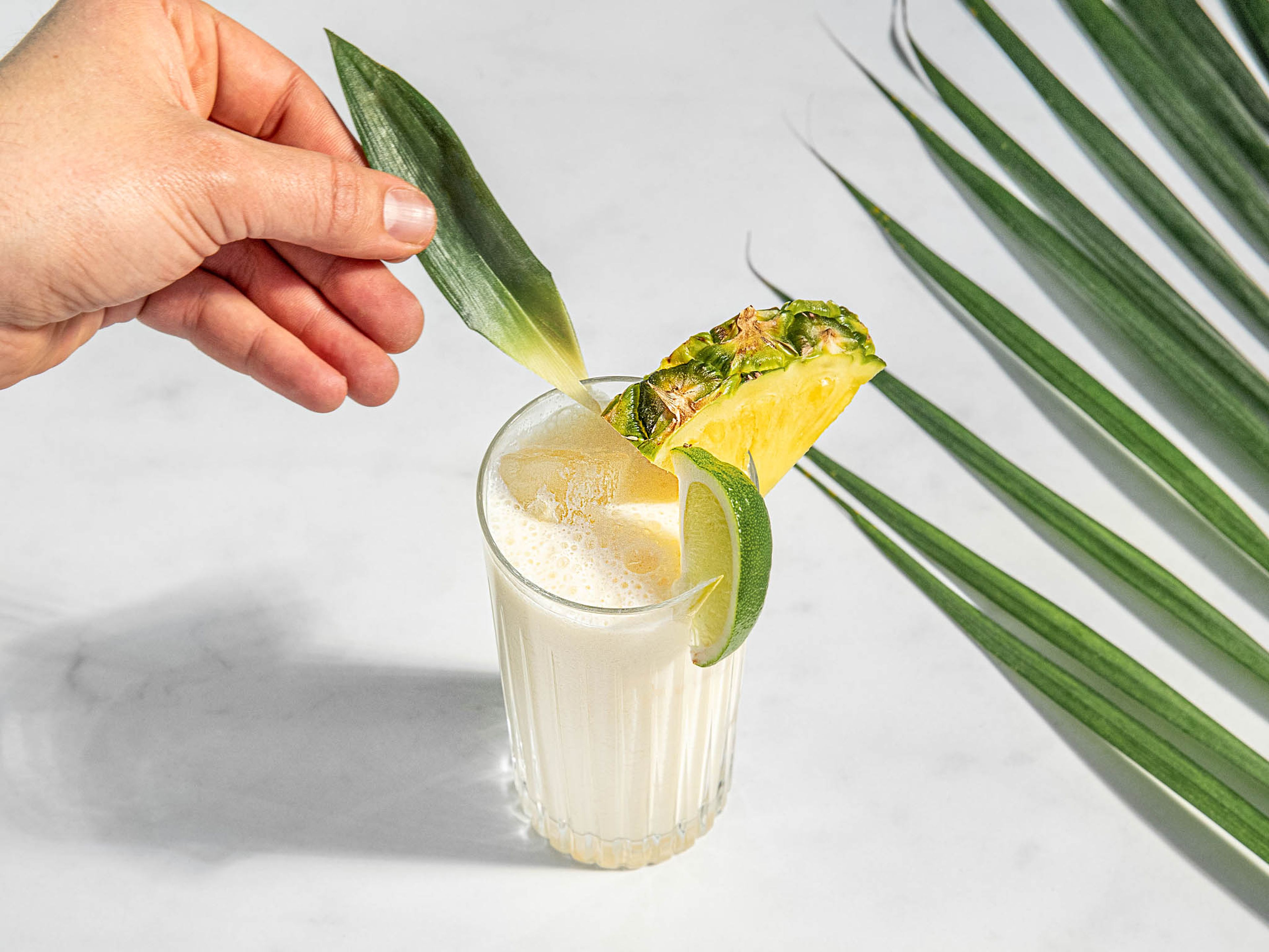 Eiswürfel in hohe Gläser geben und den Ananas-Kokos-Shake darübergießen. Mit Ananasblatt, Ananasscheiben und Limettenspalten servieren. Prost!