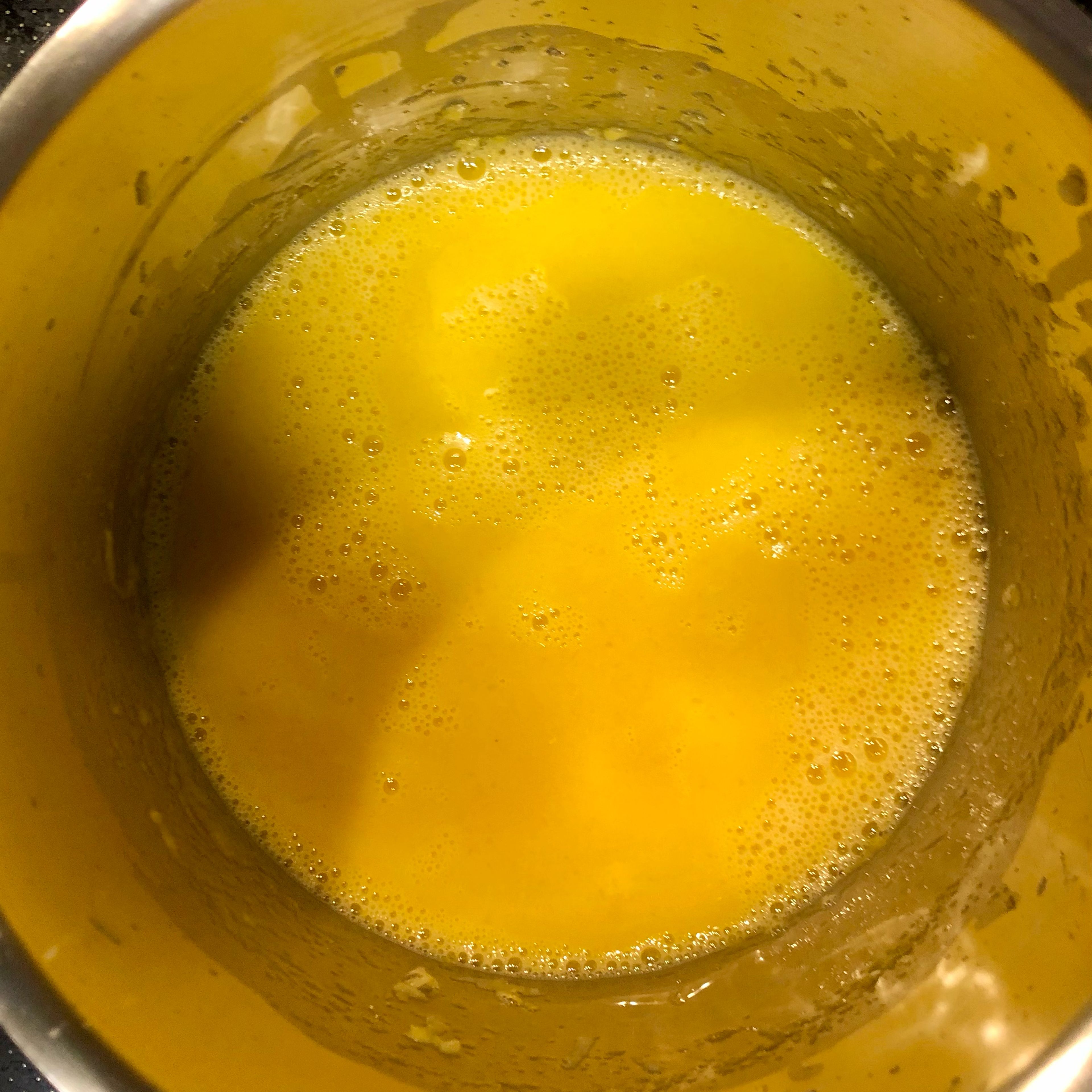 Nun werden drei Eigelbe und frisch gepresster Zitronensaft mit dem Schneebesen untergerührt. Jetzt wird 10 Minuten lang unter ständigem Rühren bei kleiner bis mittlerer Hitze der Pudding gekocht, bis er dickflüssig und samtig ist. Wenn dies zutrifft, wird er vom Herd genommen und 1 EL kalte Butter sowie 1/2 TL Vanilleextrakt werden mit rein gerührt. Danach muss der Pudding vollständig auskühlen.