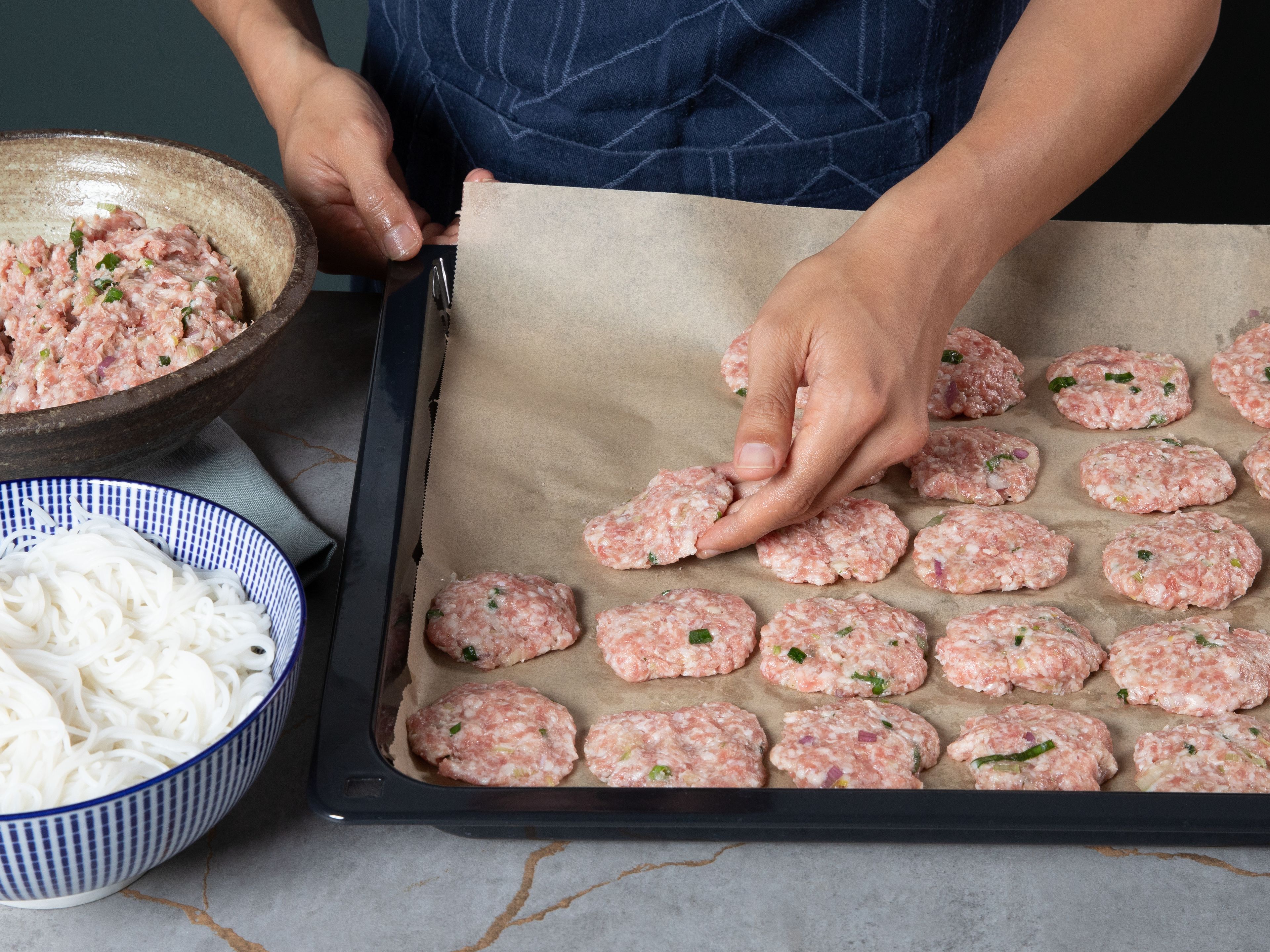 Die marinierte Hackmischung zu mundgerechten Patties formen und auf einem mit Backpapier ausgelegten Backblech im vorgeheizten Ofen bei 200°C Ober-/Unterhitze ca. 15–20 Min. goldbraun backen. Währenddessen die Vermicelli-Nudeln nach Packungsanweisung kochen, abgießen und beiseitestellen.
