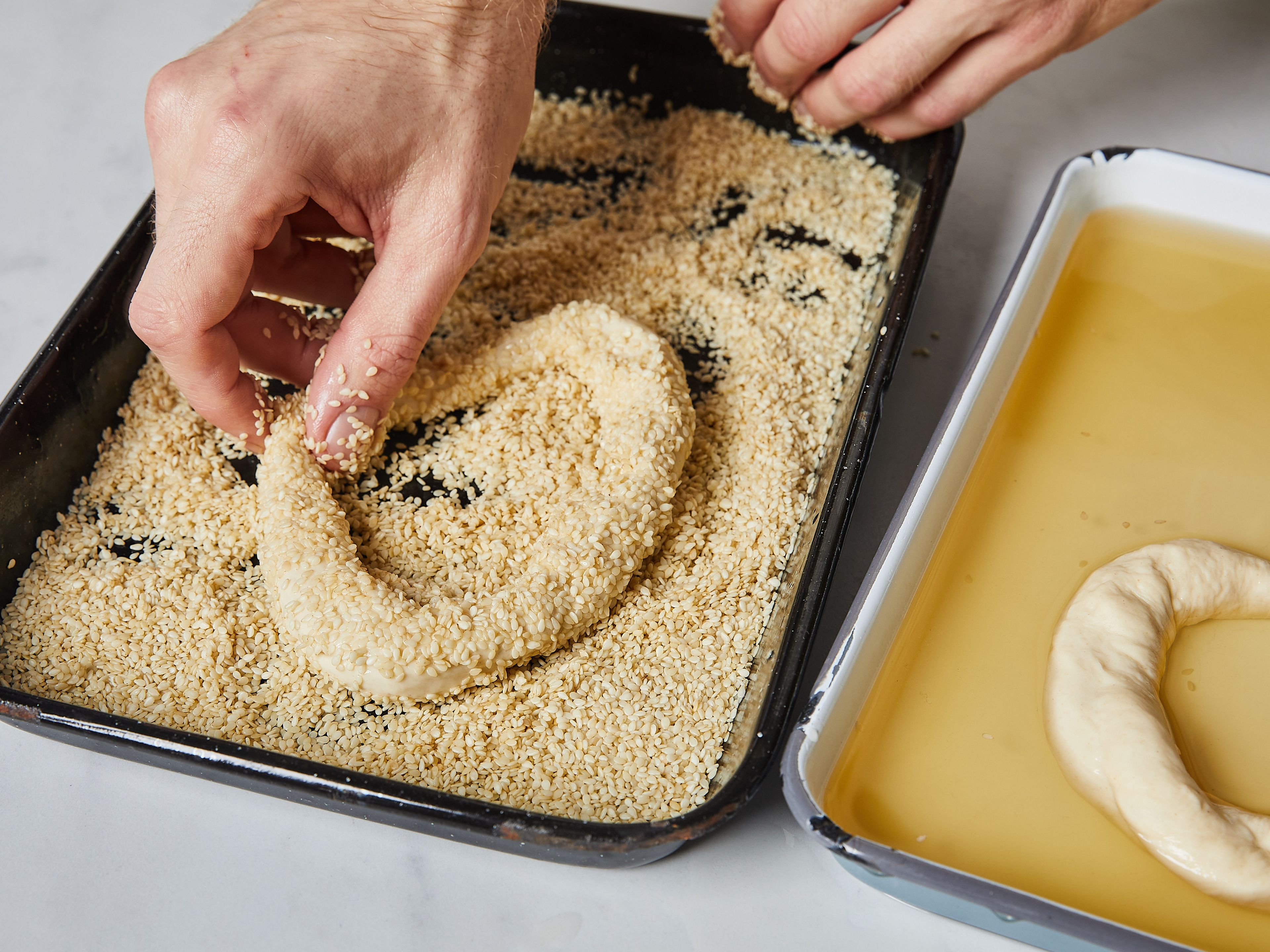 Prepare two baking sheets with parchment paper. Dip the ring into the honey water, and then transfer to sesame seeds. Make sure the ring is completely covered in sesame seeds before transferring to baking sheet with parchment paper. Repeat with remaining rings. Let the rings rest for 45 min.