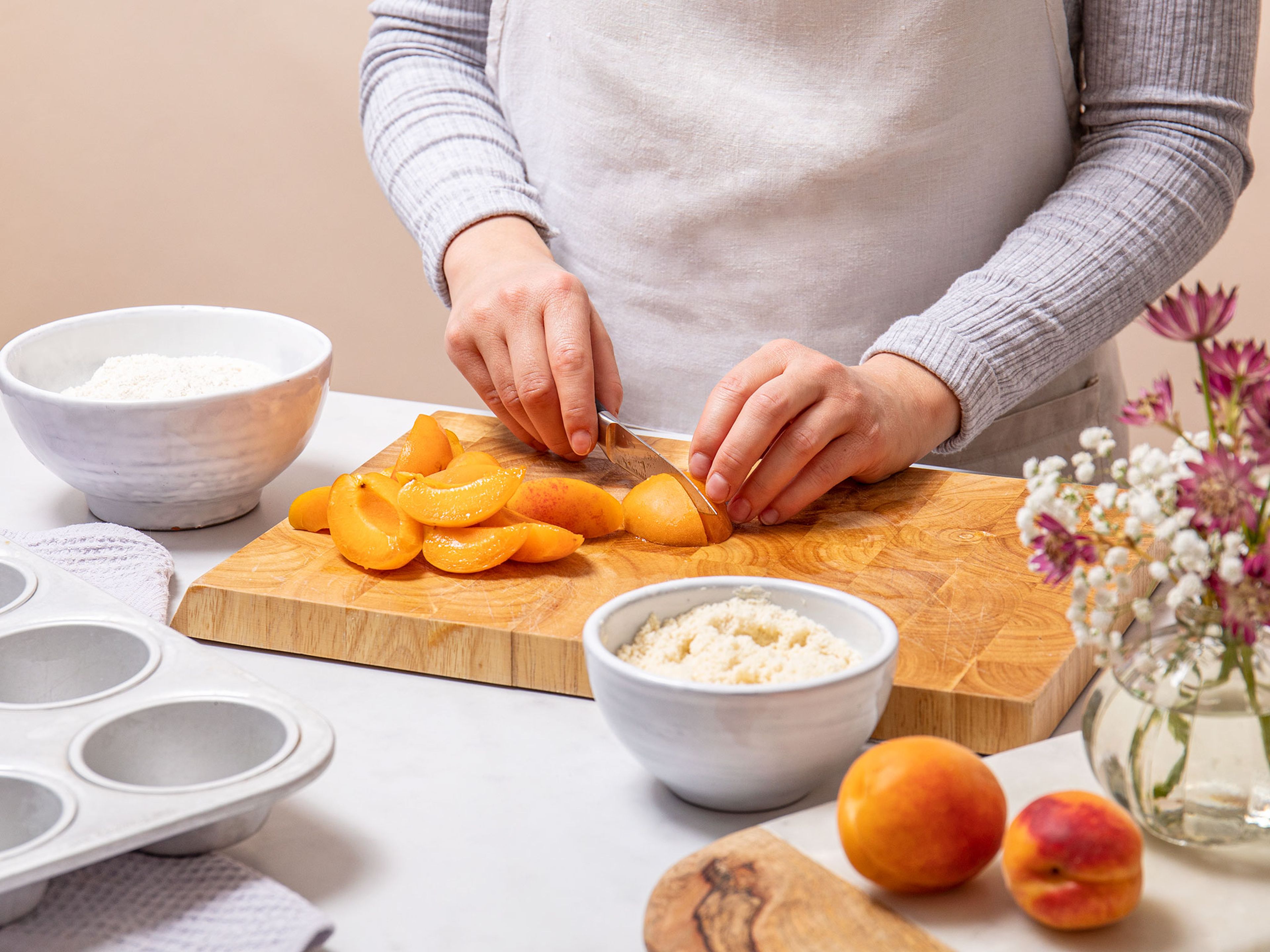 Den Ofen auf 180°C vorheizen. Die Muffinform mit Butter einfetten. Die Aprikosen jeweils in 8 Spalten schneiden.