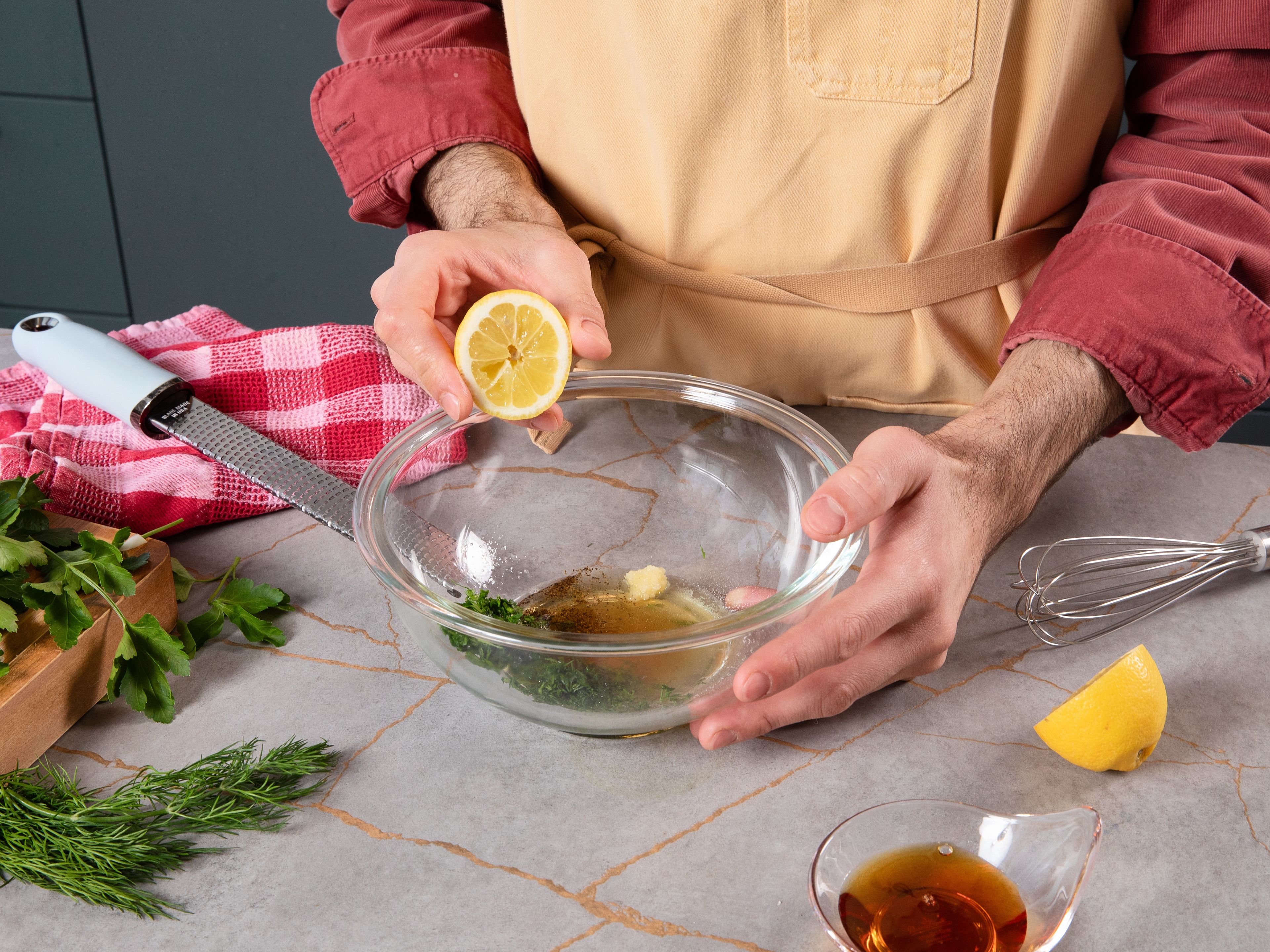 While the cabbages are roasting, prepare a simple vinaigrette. Finely chop half of the parsley and dill, setting the other half aside for garnishing. Finely chop, press or grate the garlic. Then place the garlic and chopped herbs in a bowl. Grate some lemon zest and squeeze the lemon juice, then add to the bowl along with the olive oil, salt and pepper. Whisk everything together well.