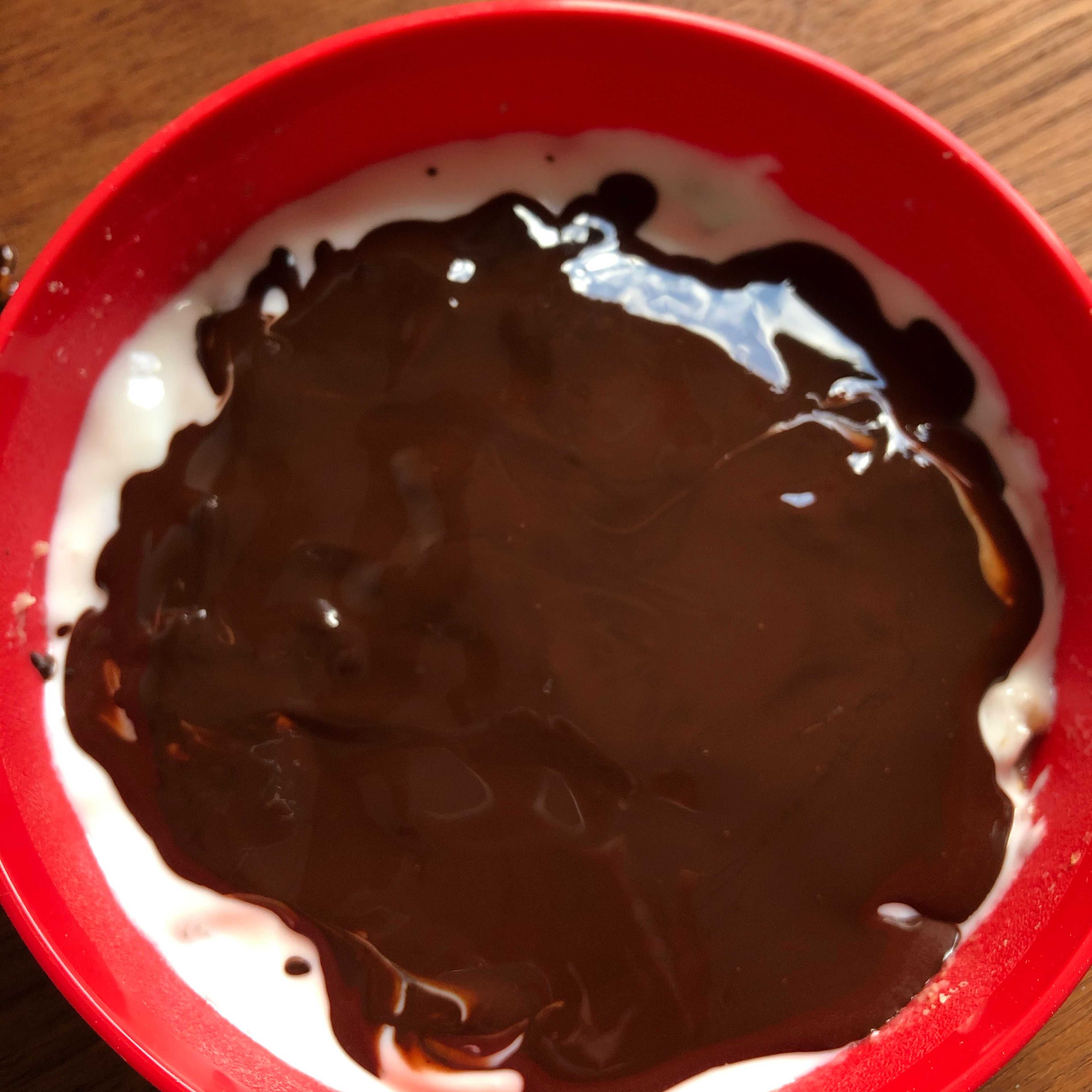 Wenn die Schokolade geschmolzen ist, kann sie über die Joghurt-Schicht gegeben und verstrichen werden. Dabei sollte sich die Schokolade nicht zu sehr mit dem Joghurt vermischen, damit wir am Ende eine schöne Schokoschicht bekommen.