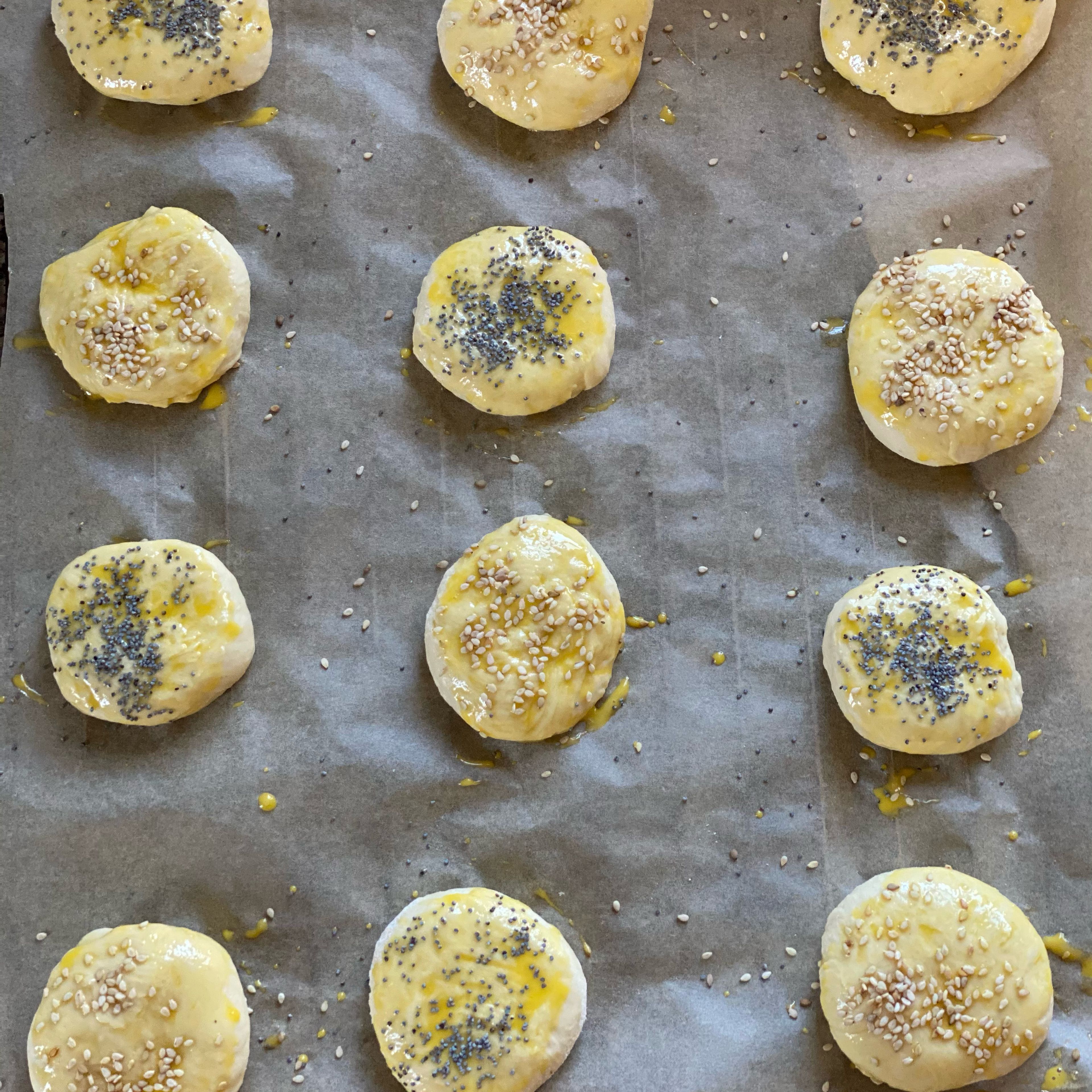 1 Eigelb mit 20ml Milch verrühren, mit einem Pinsel die Buns bestreichen und mit Sesam und Mohn bestreuen. Backofen auf 180Grad Ober-Unterhitze aufheizen und die Buns 20min goldgelb backen.