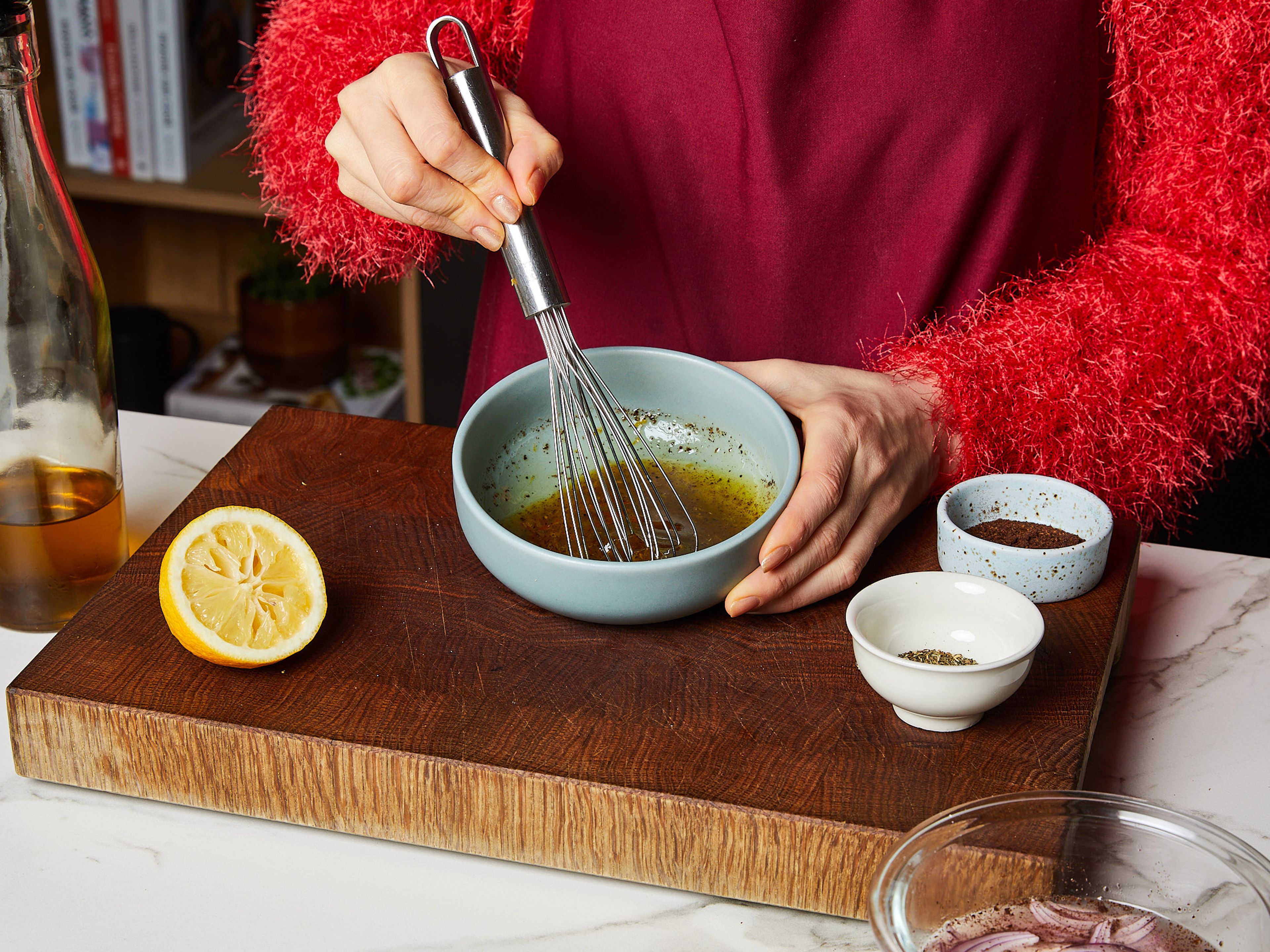 Währenddessen in der zuvor für die Marinade verwendeten kleinen Schüssel das Dressing vorbereiten. Die verbliebene halbe Zitrone darin abreiben und auspressen, das restliche Olivenöl, Sumach, getrocknete Minze und eine Prise Zucker hinzufügen und gut verrühren. Mit Salz und Pfeffer abschmecken und beiseitestellen.