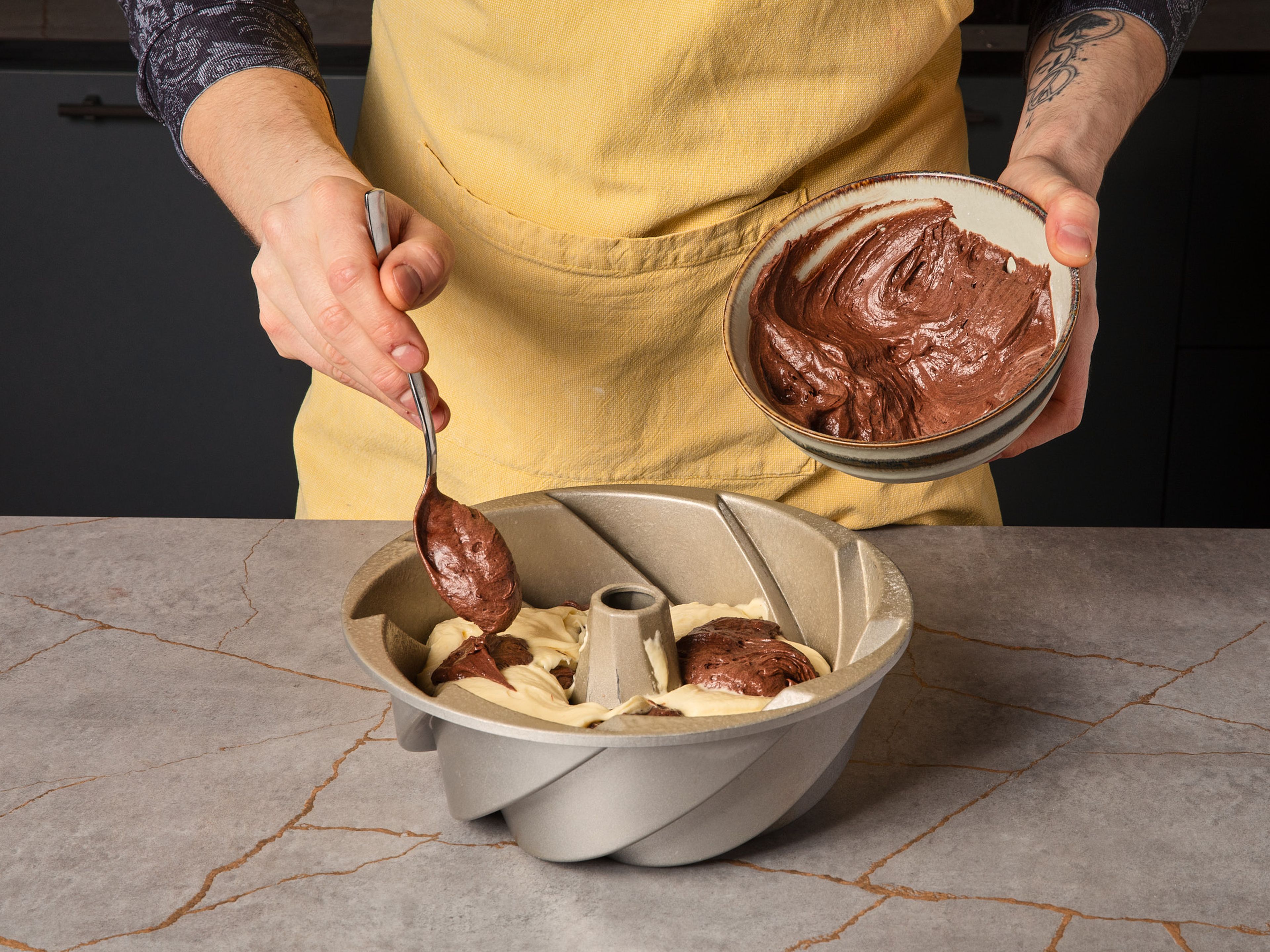 Gugelhupfform einfetten und mit Mehl bestäuben. Den Teig abwechselnd in Schichten in die Form geben. Bei 180°C ca. 50–60 Min. backen. Anschließend aus dem Ofen nehmen und 15–20 Min. in der Form abkühlen lassen, dann auf ein Kuchengitter stürzen und vollständig auskühlen lassen.
