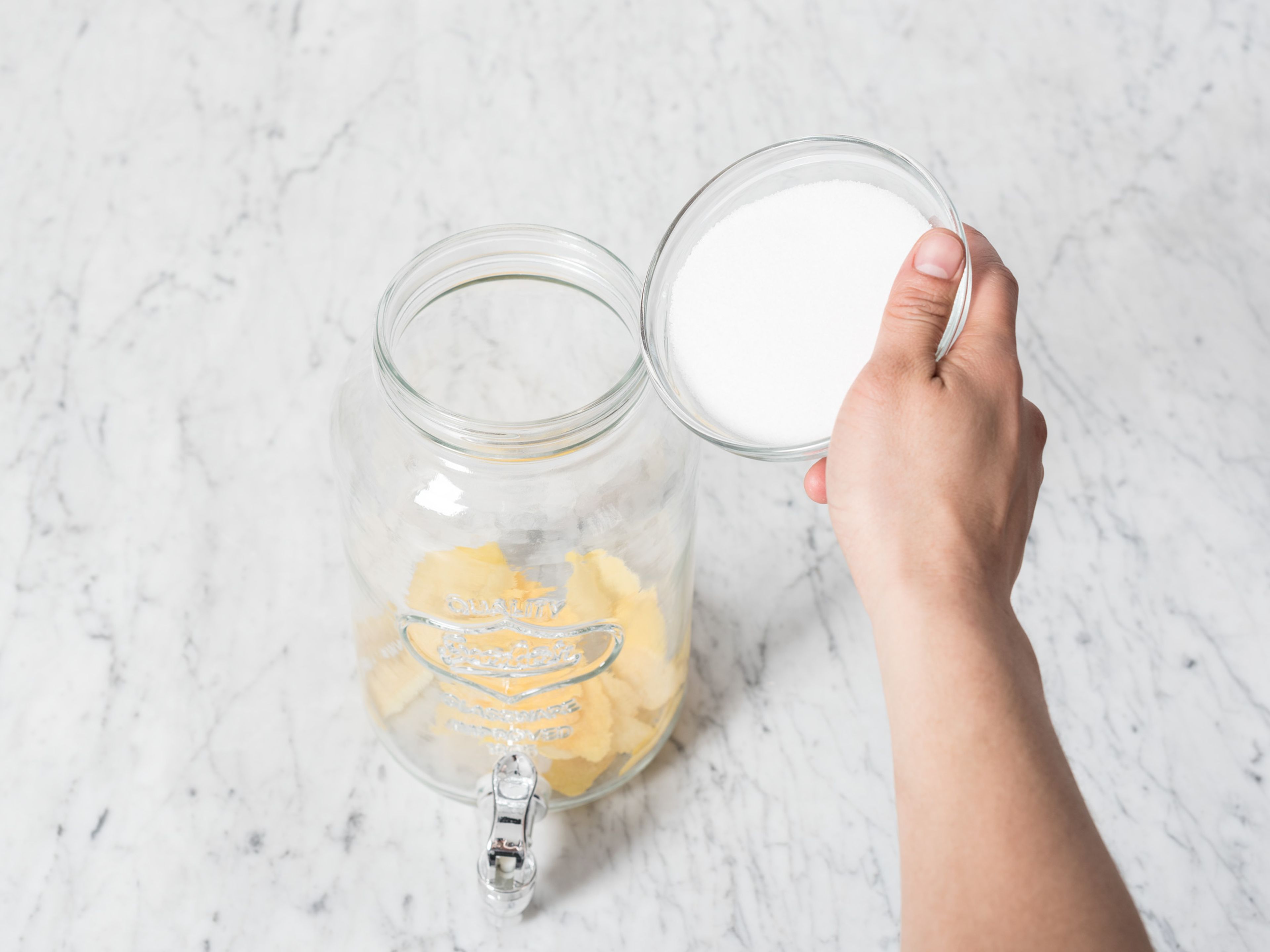 Die Schale von 2/3 der Zitronen schälen. Alle Zitronen auspressen. Zitronenschalen und Zucker in einen großen Krug geben und ca. 15 Min. stehen lassen.