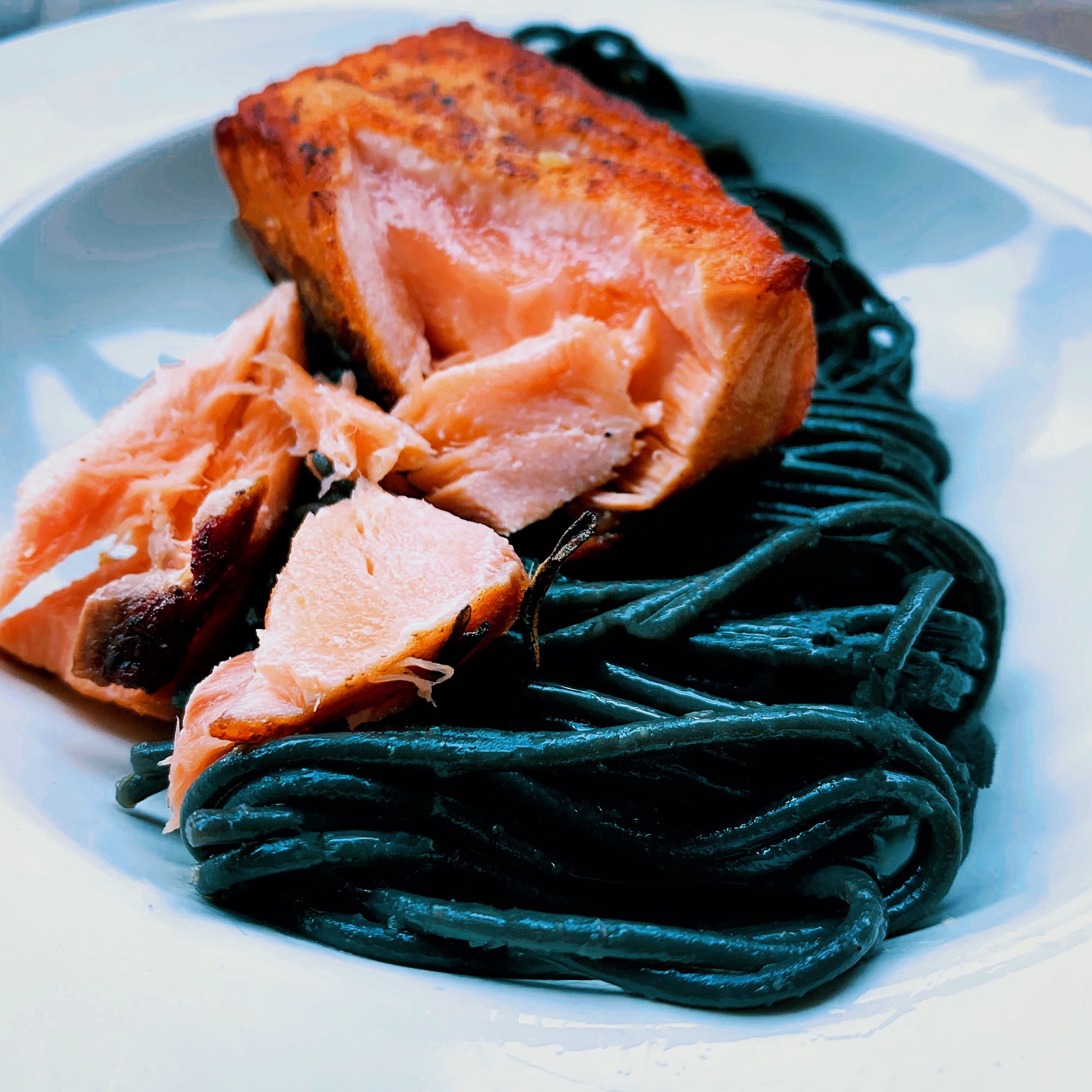 Toss pasta into the pan and plate on a bright white pasta dish. Place salmon on top and serve.