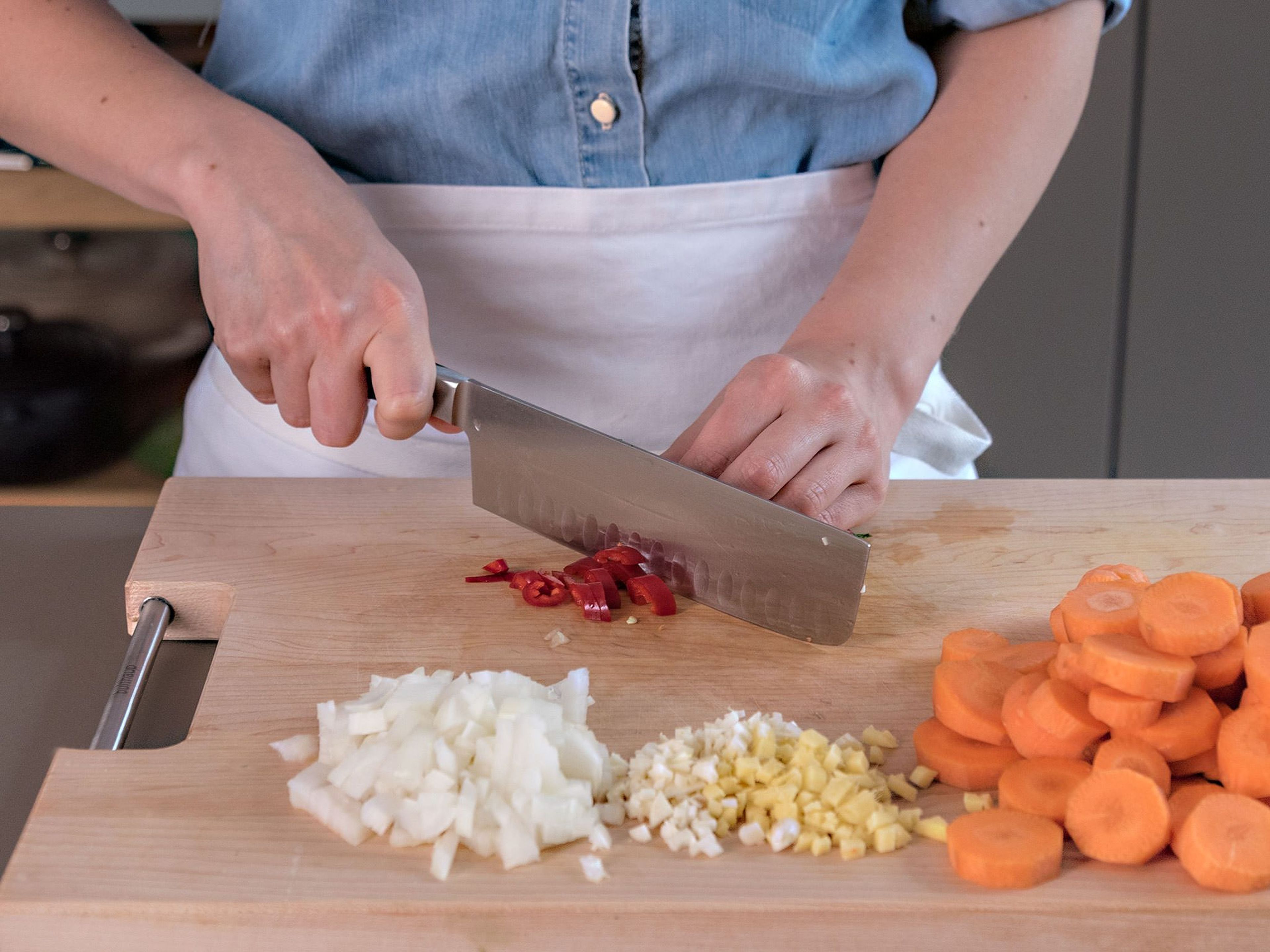 Karotten schälen und in Scheiben schneiden. Zwiebel, Knoblauch, Ingwer und Chili hacken.