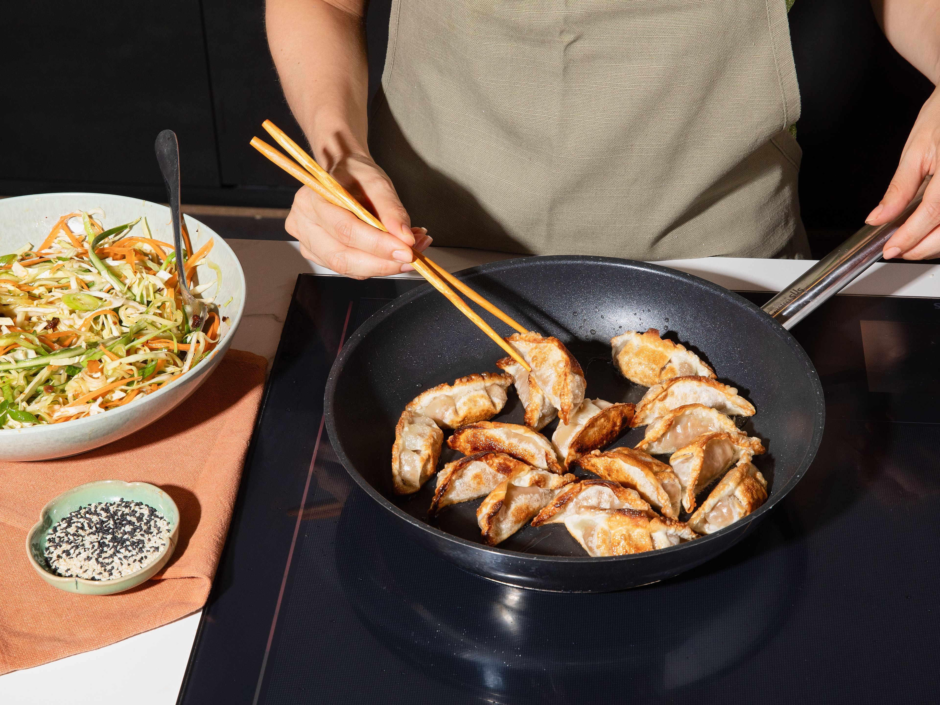 Meanwhile, prepare dumplings according to package instructions. Fry in a large frying pan with a little oil until golden brown and crispy. Arrange dumplings on salad and sprinkle with cilantro, reserved spring onion greens, and sesame.