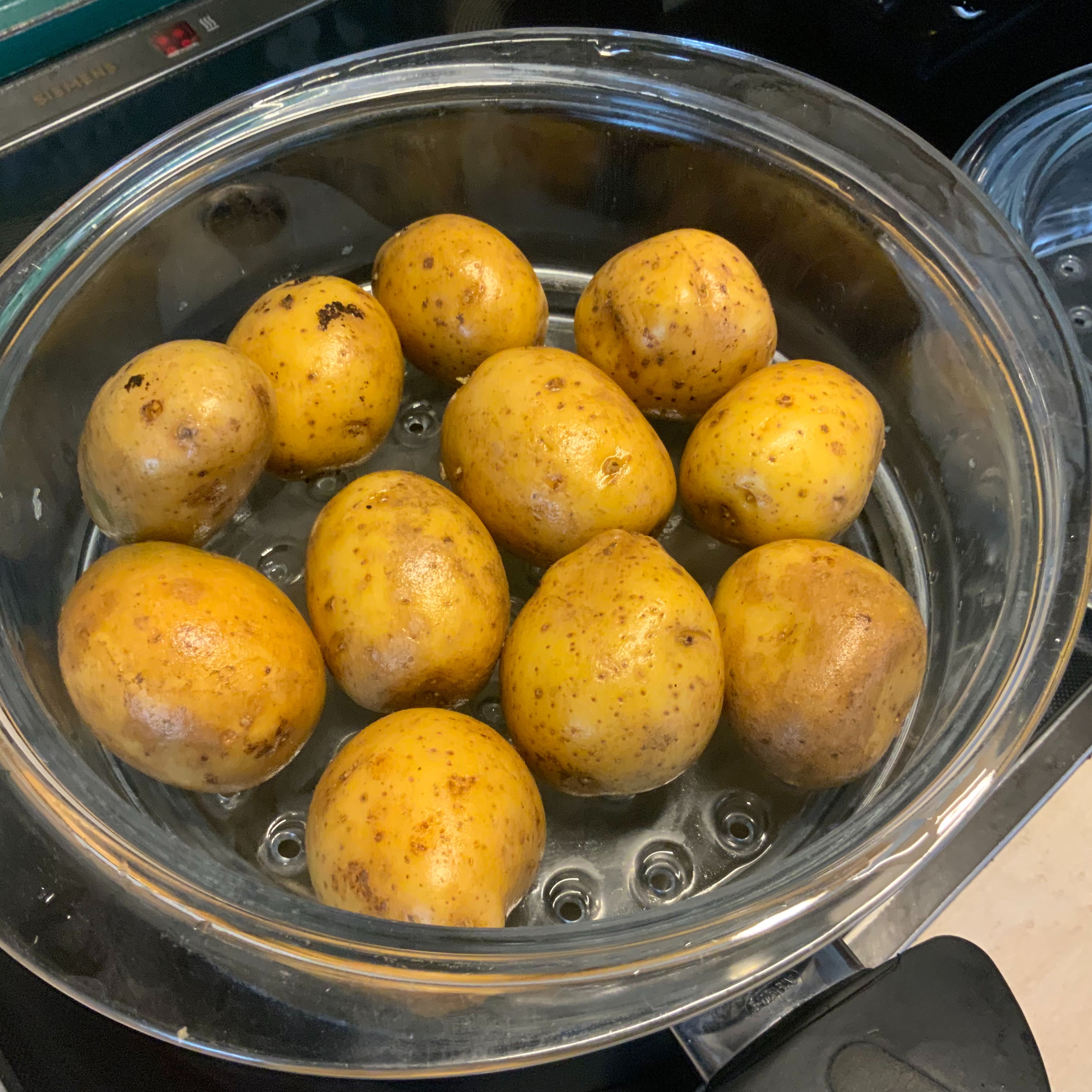 Die kleinen Kartoffeln waschen, als Pellkartoffeln im Dämpfer oder kochendem Wasser ca. 25 Minuten - je nach Größe - kochen und danach schälen.