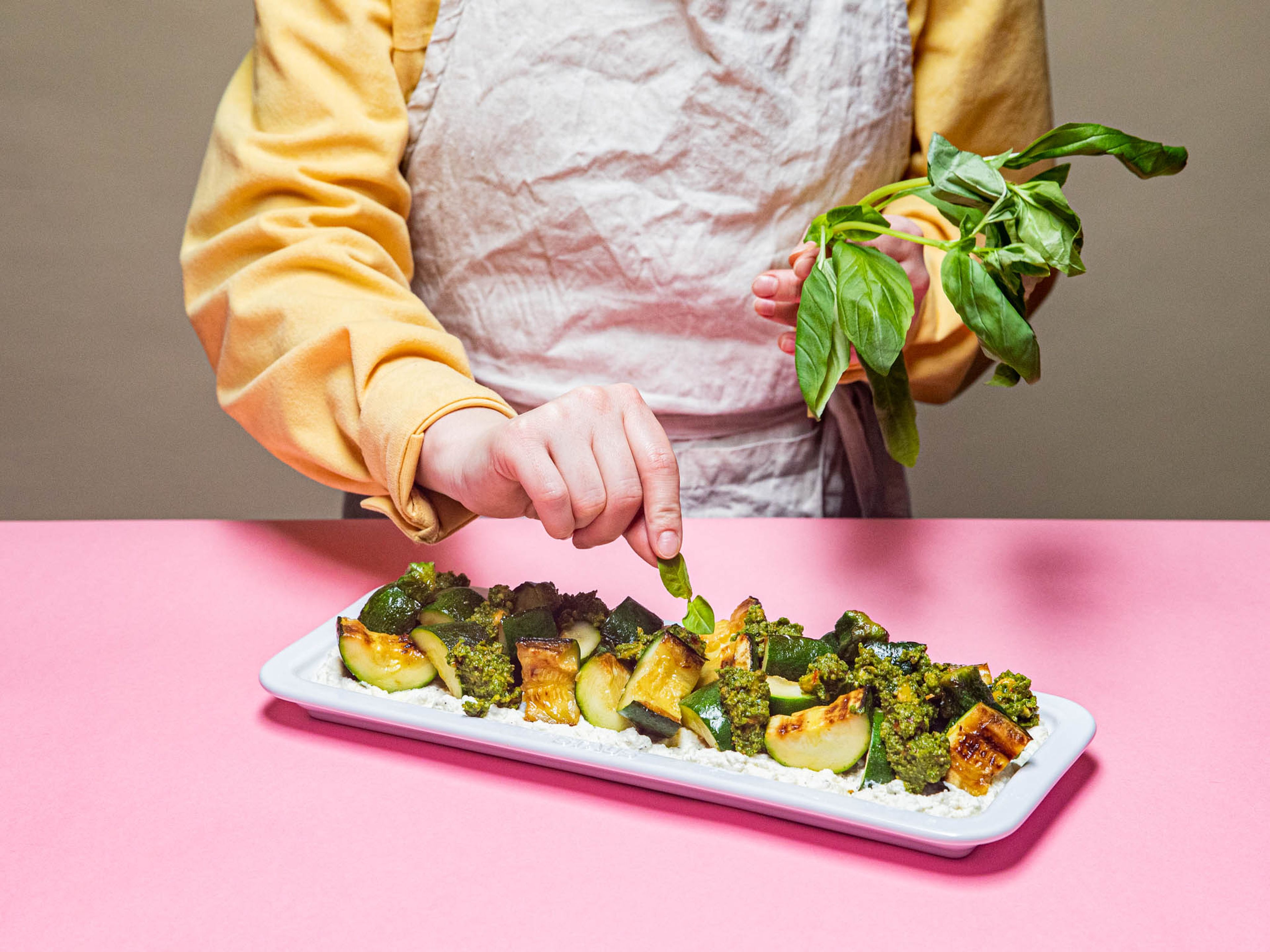 Ricotta auf einem Teller anrichten, die Zucchinistückchen darauf verteilen und mit dem Pesto beträufeln. Mit dem beiseitegelegten Basilikum, Petersilie und Haselnüssen bestreuen. Mit Salz und Pfeffer abschmecken und genießen!