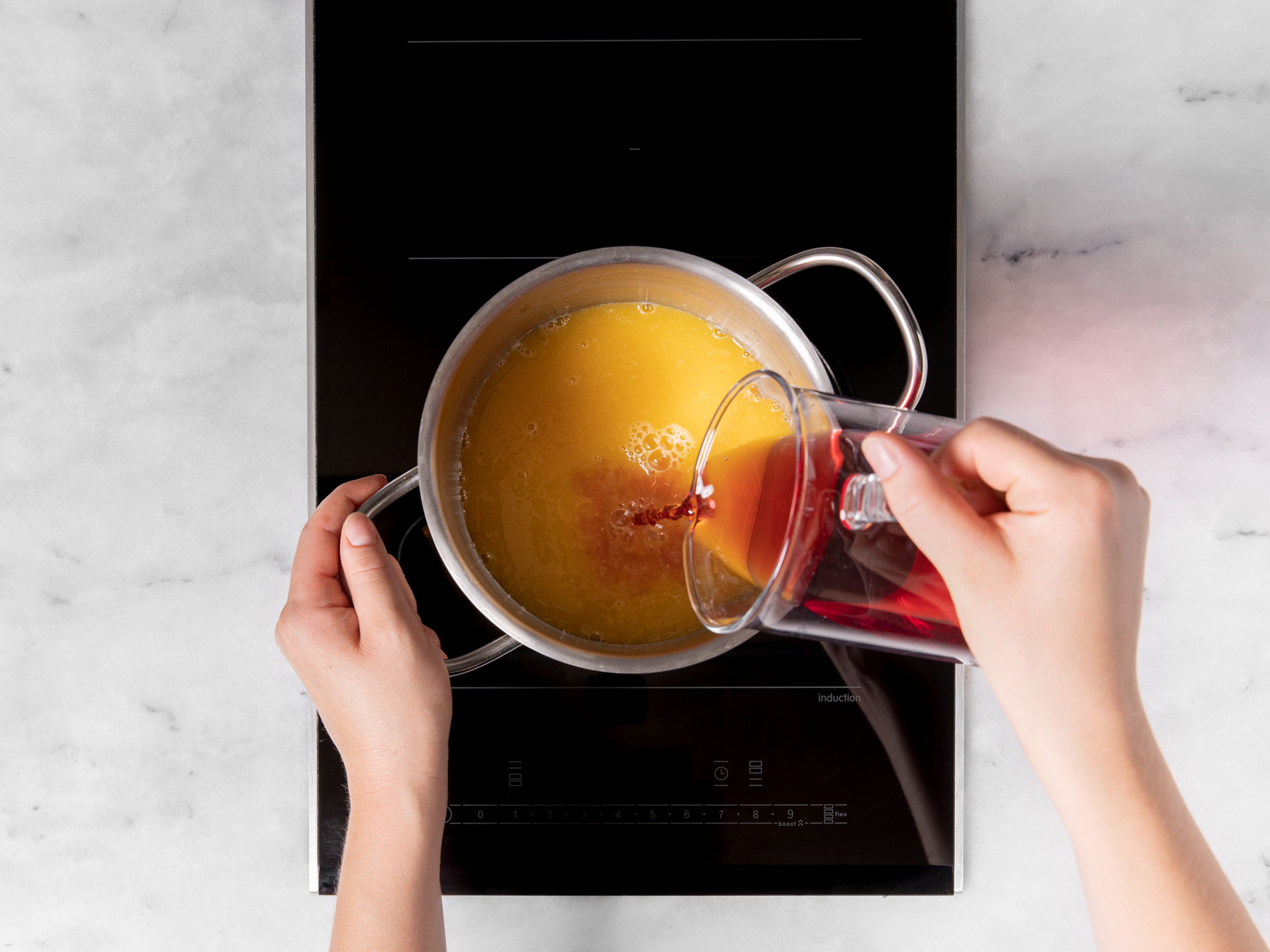 Erhitze in einem Topf Cranberrysaft und Orangensaft bei mittlerer Hitze. Sobald er erwärmt ist, gib ihn in die Teekanne oder die Isolierflasche. Warm genießen!