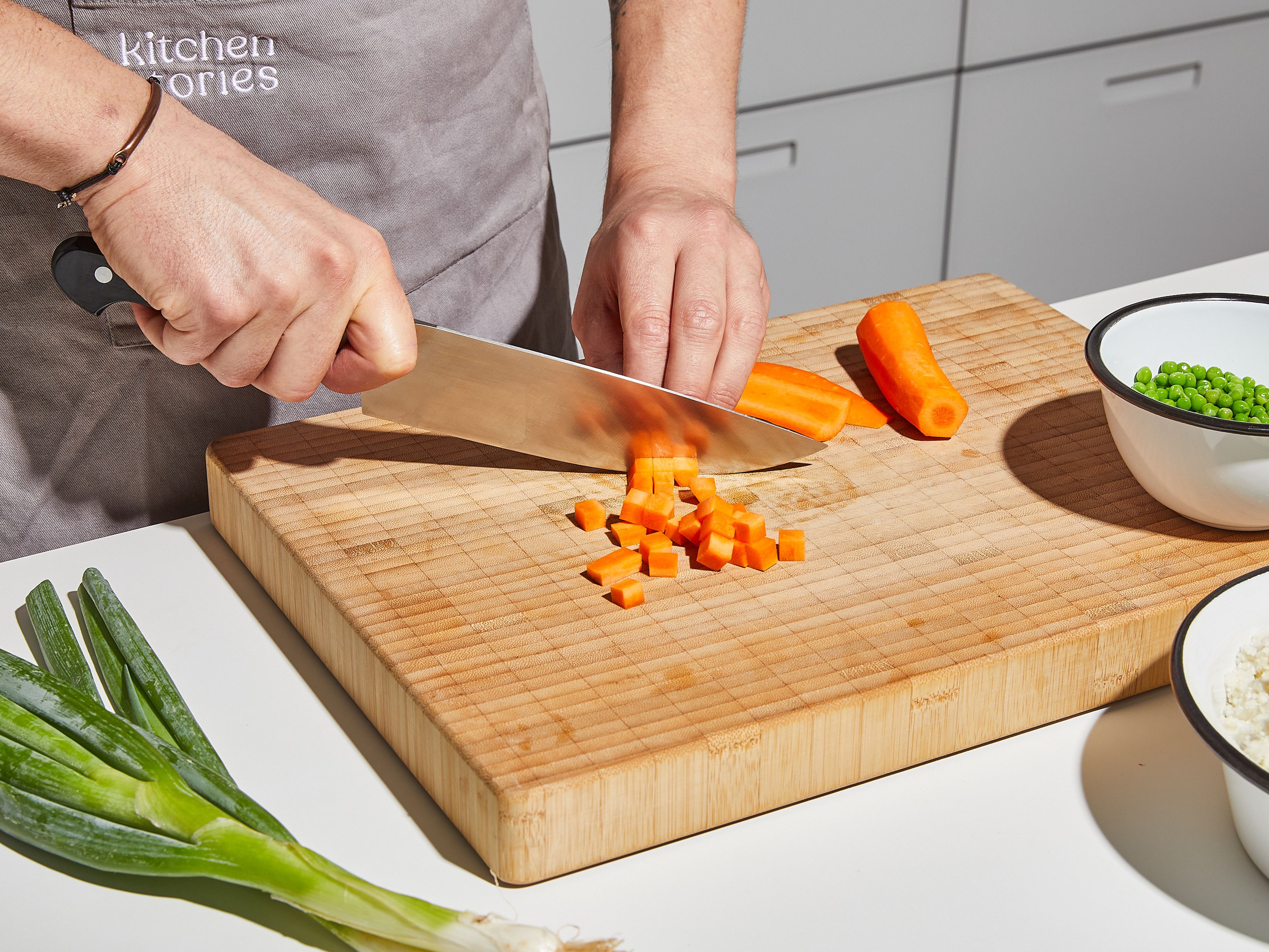 In the meantime, peel the carrot and cut into small cubes. Peel and finely chop the onion and garlic. Cut scallions into fine rings, and separate the white and green parts.