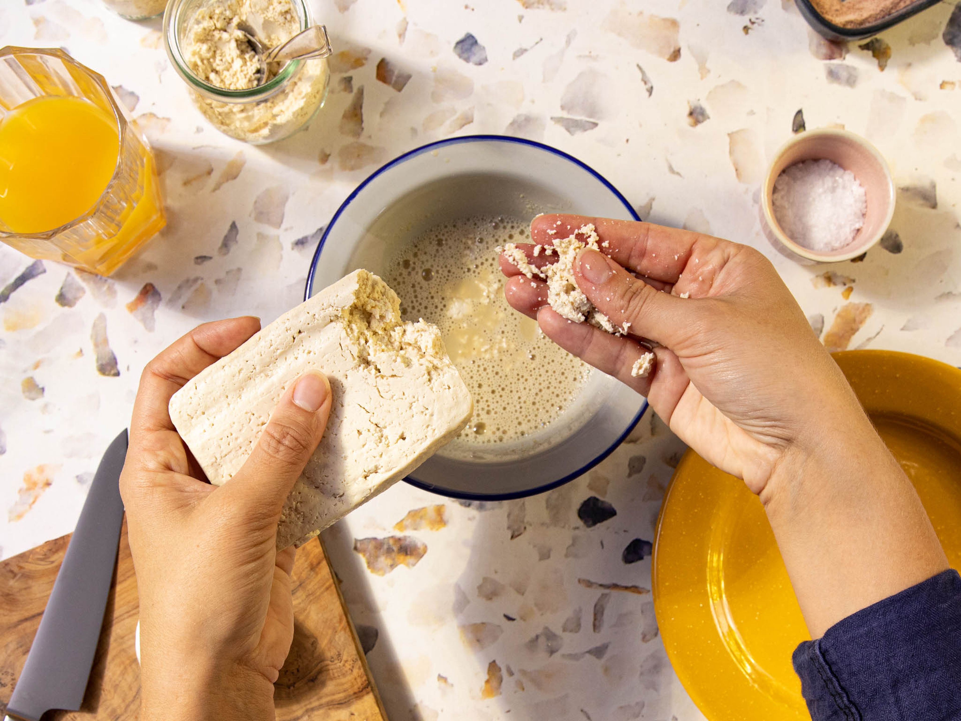 Tofu mit den Händen in kleinere Stücke zerbröseln und direkt in die Schüssel zur Sojamilch-Mehl-Mischung geben. Großzügig mit Salz und Pfeffer würzen und vermengen.