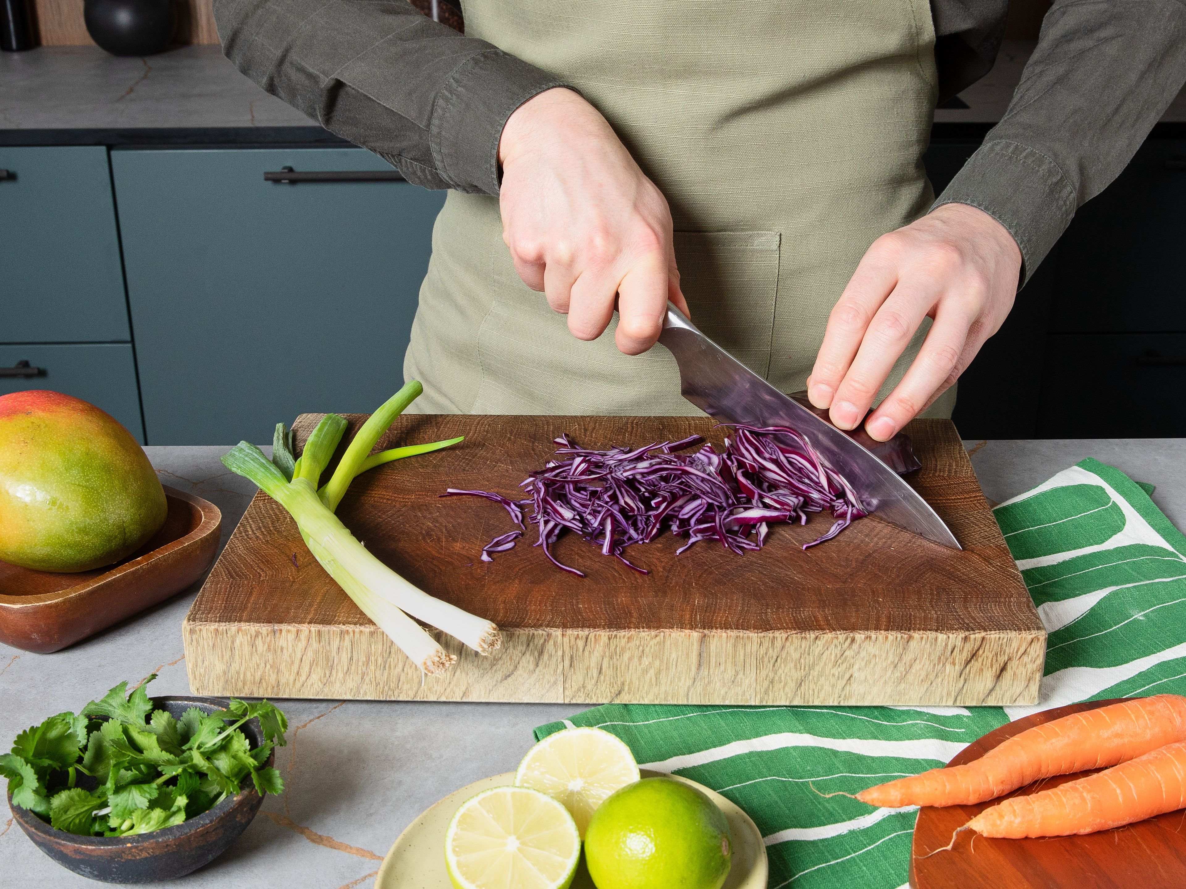 Einen Topf mit Wasser zum Kochen bringen, Edamame darin nach Packungsempfehlung garen, anschließend abgießen, beiseitestellen und ggf. warm halten. Rotkohl vom Strunk befreien, sehr fein schneiden, in eine Schüssel geben und mit Limettensaft, Salz und Pfeffer abschmecken. Karotten schälen und grob raspeln, Frühlingszwiebeln in feine Ringe schneiden, Koriander von den Stielen zupfen.