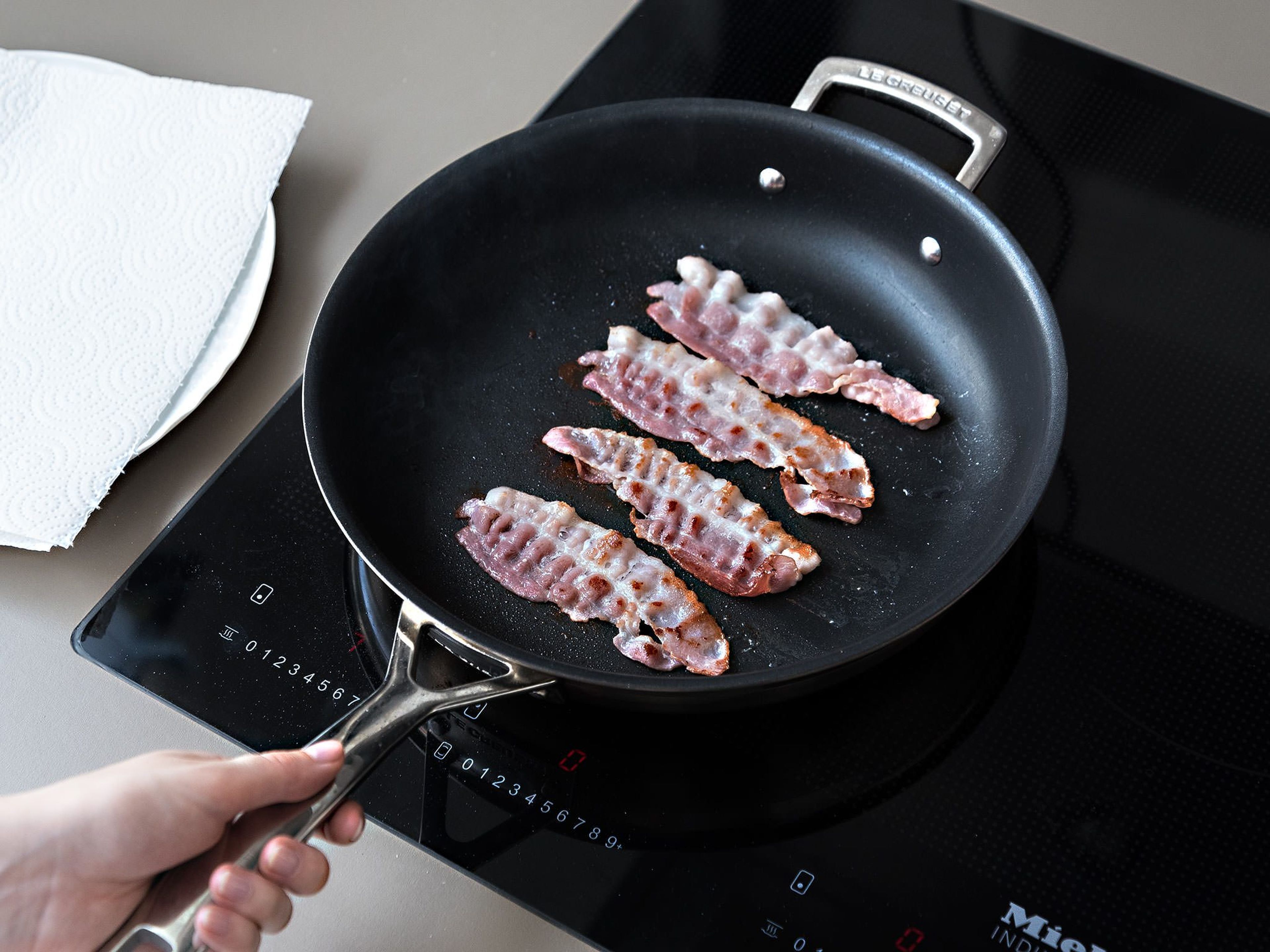 Meanwhile, fry the bacon both sides until crisp, then remove bacon from the pan. Add remaining butter and honey to pan with rendered bacon fat. Remove the carrots from the oven and toss them in the honey-butter mixture until they have become lightly caramelized.