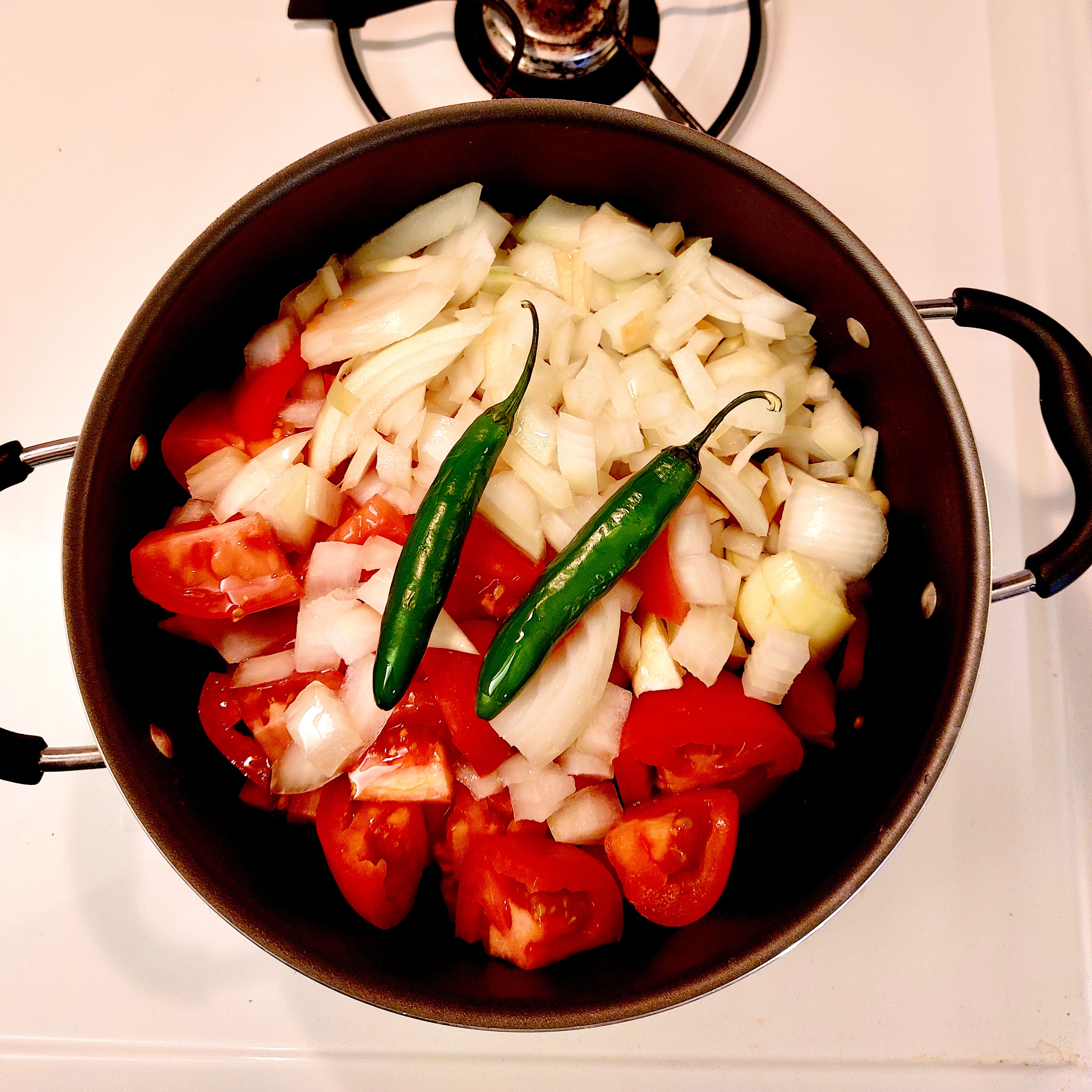 Preheat a large pan and add tomatoes, onions, garlic and serrano. Drizzle lightly with olive oil and close with a lid. Let everything cook over medium heat for 25 minutes.