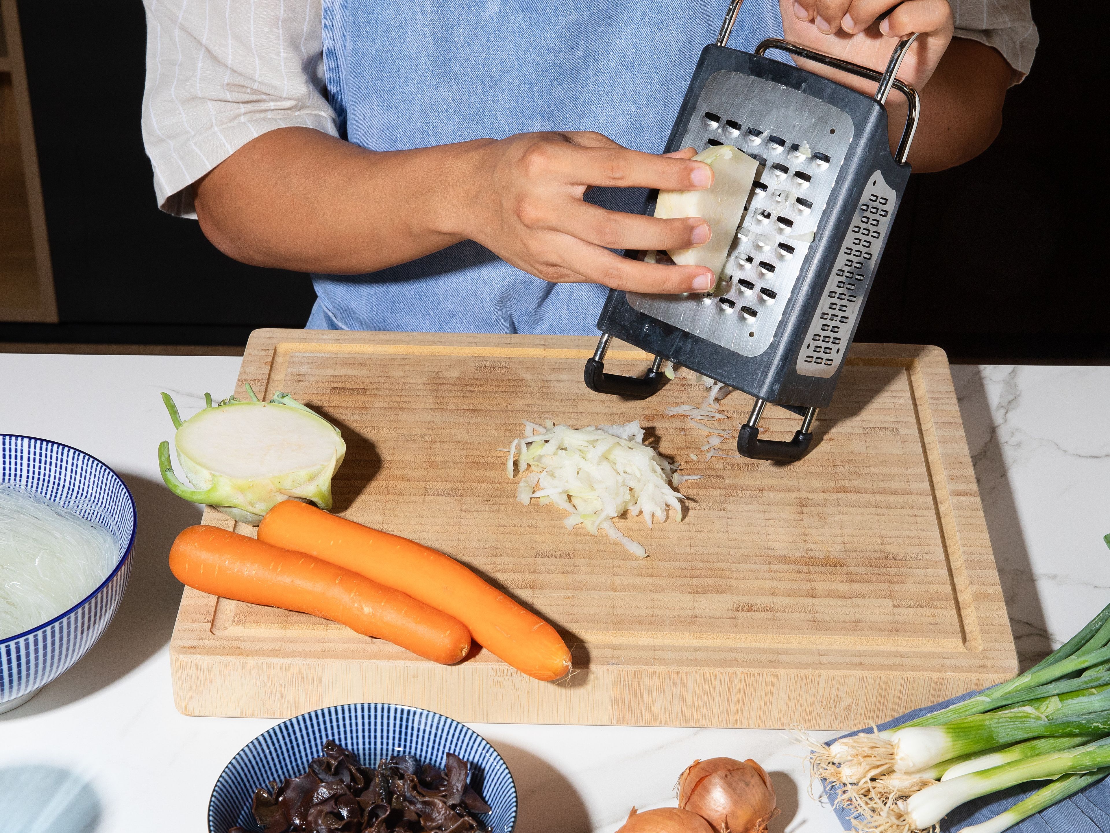 Soak glass noodles and wood ear mushrooms in lukewarm water until soft, then drain. Grate the kohlrabi and carrot, peel and dice the onion, slice the scallions into rings, and crumble the tofu into even crumbs.