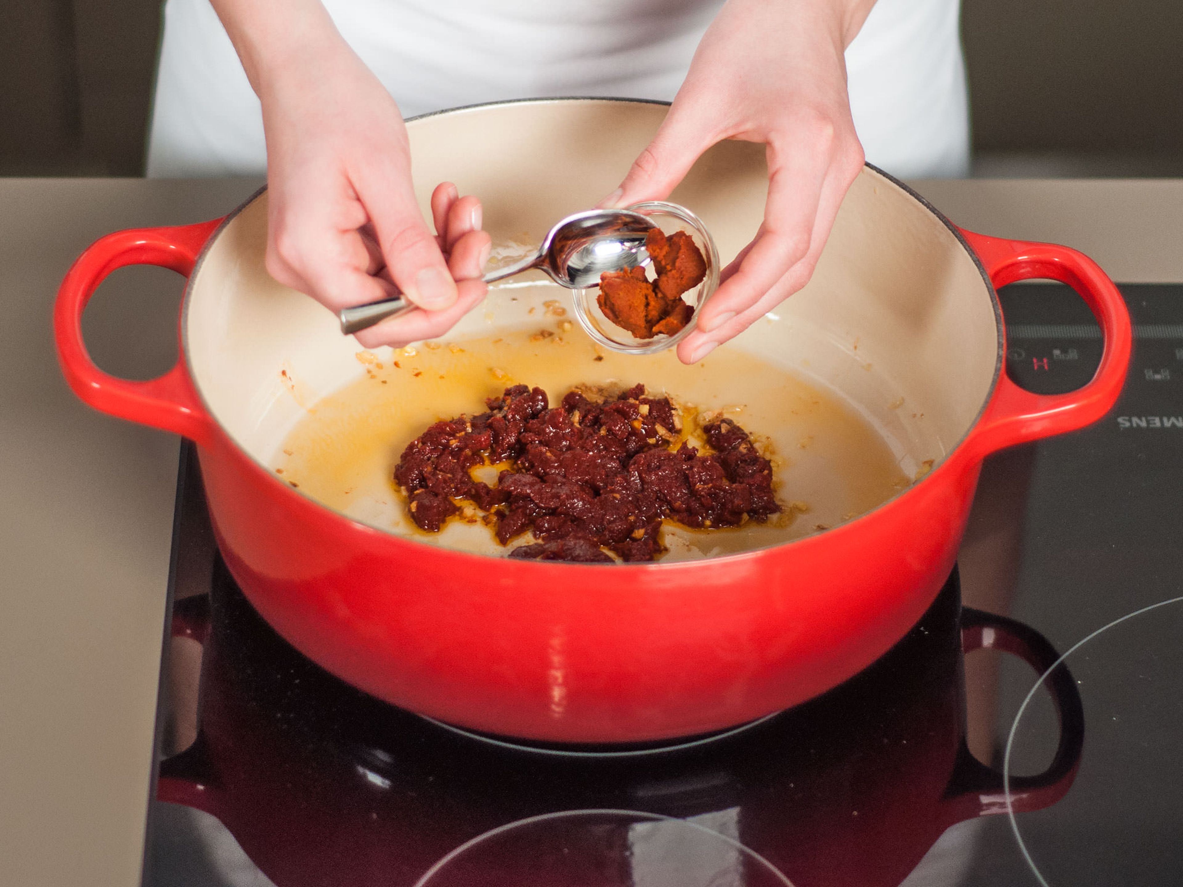 Rote Currypaste hinzugeben und leicht anbraten. Gelegentlich umrühren, um anbrennen zu vermeiden.